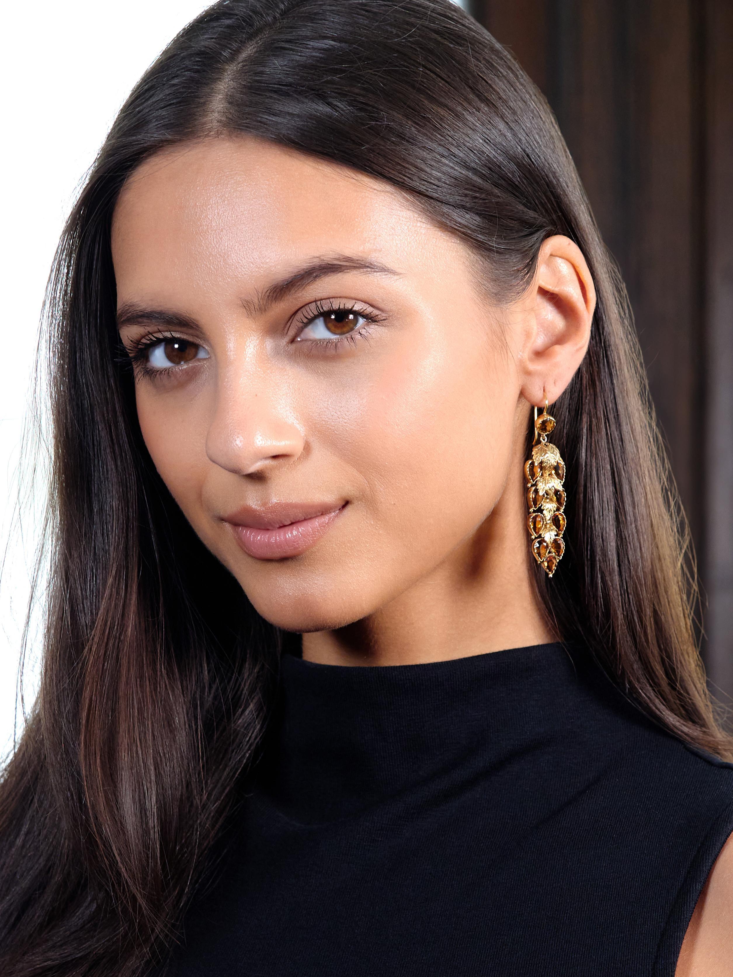 Designed as round surmounts suspending tiered cluster drops
Comprised of bezel set round and pear cut citrines
Weighing approximately 11.60 carats total
Transparent medium brownish orange in color
Accented by gold foliate appliqué