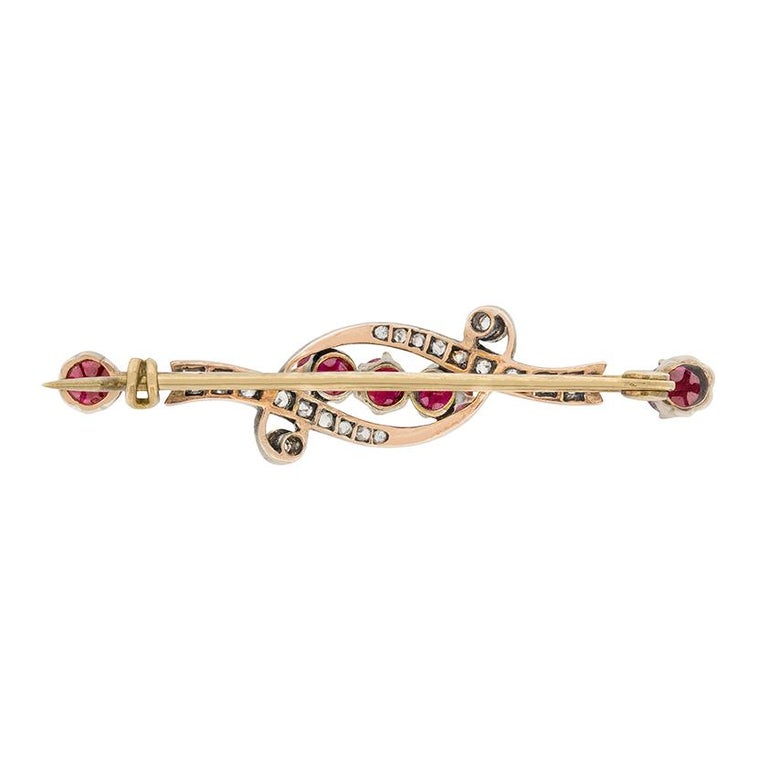 Five rubies are surrounded by rose cut diamonds in this Victorian brooch. The rubies are old cut, and are a slightly purplish red. Each ruby is 0.25 carat. Two diamond studded swirls surround the rubies, containing 0.10 carat of rose cut diamonds.