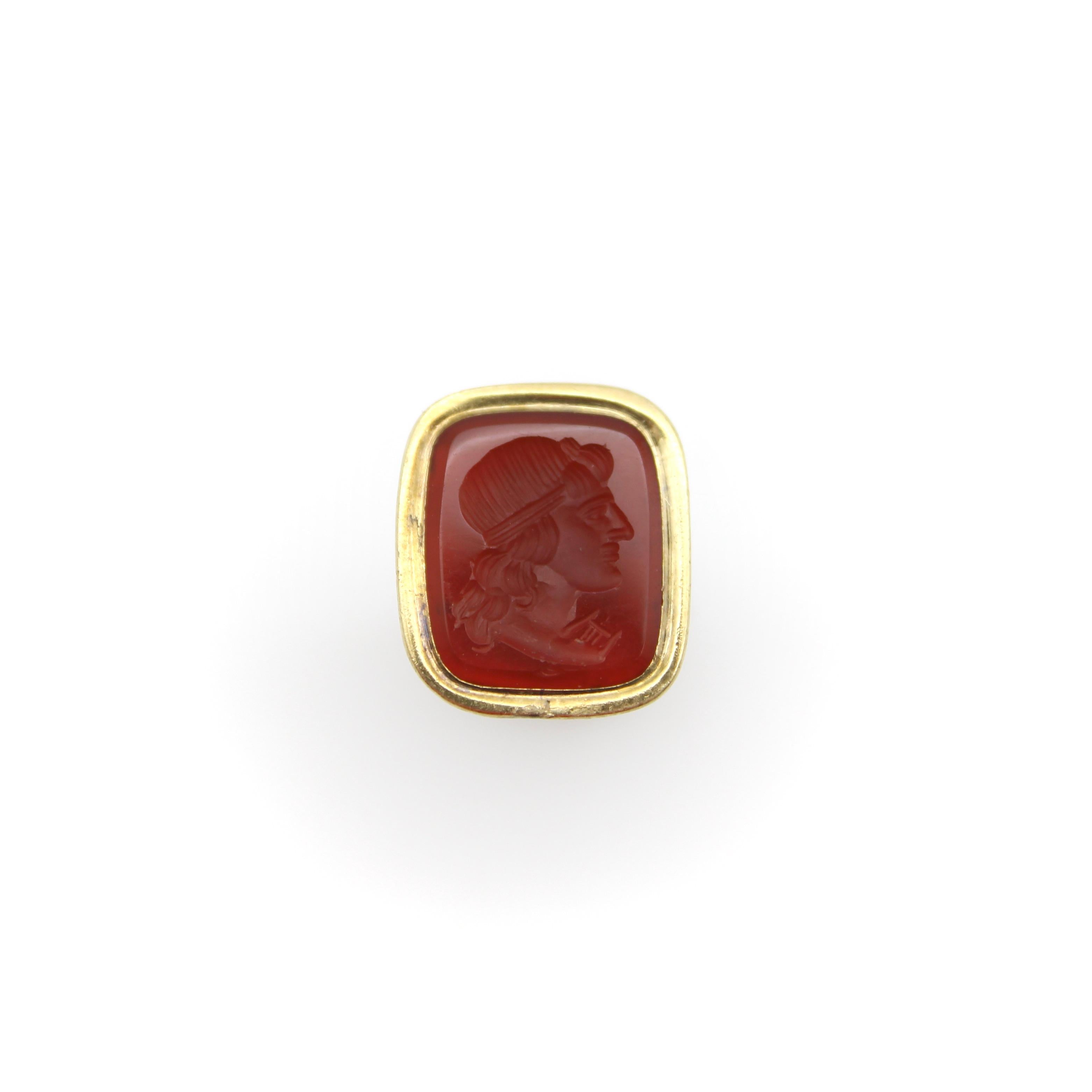 Originally a watch fob, this unique Victorian era antique can also be worn as a fashionable pendant. The fob is 12k gold-cased and features a carnelian gemstone, carved with an intaglio depicting a portrait of a mans profile. Traditionally, during