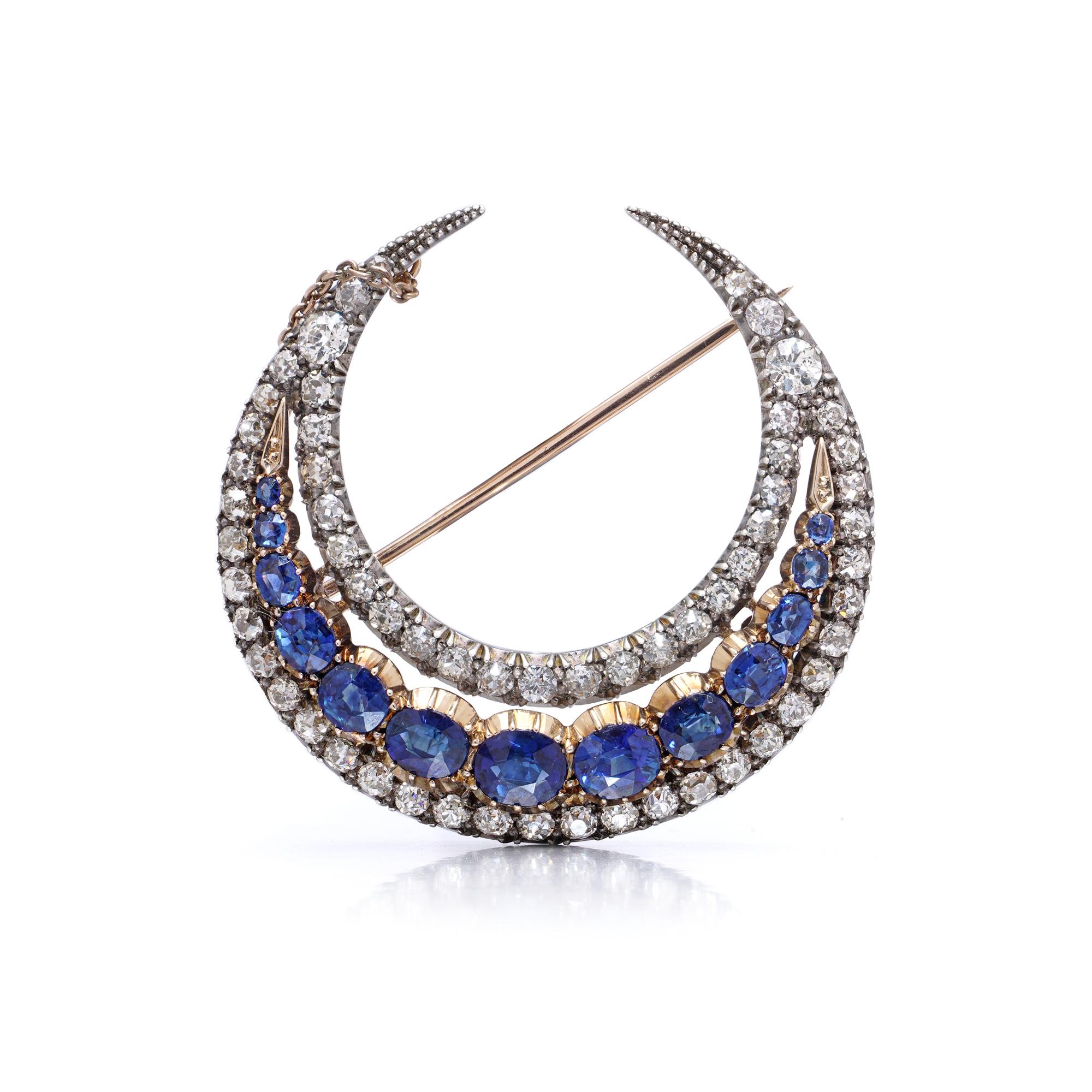 A beautifully crafted antique Victorian crescent moon brooch set with natural sapphires and old-cut diamonds. The brooch features a silver-on-gold construction typical of the mid-to-late 19th century, with 13 graduated oval mixed-cut sapphires of