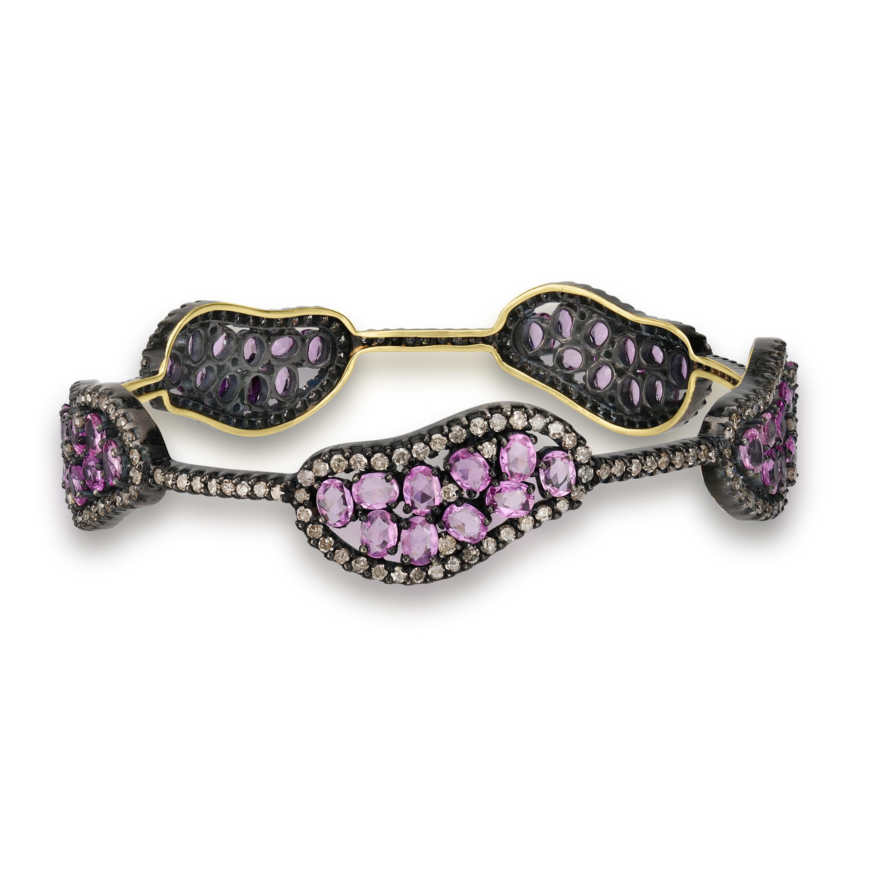 
Presenting the Victorian 13 Cttw. Pink Sapphire and Diamond Station Bangle, a captivating blend of vintage elegance and modern sophistication. This exquisite bangle is meticulously crafted from sterling silver, enhanced with a black rhodium coating