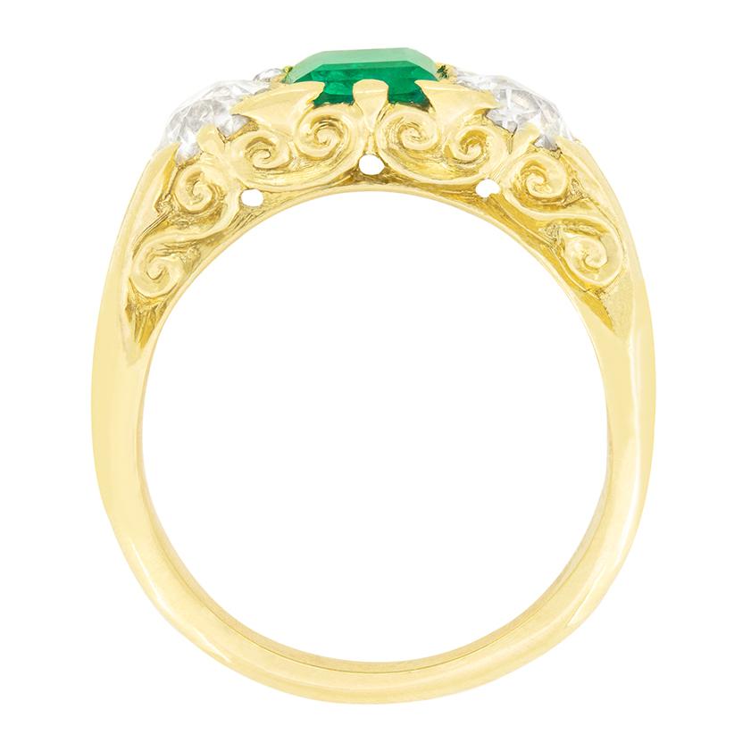 Cette magnifique pièce victorienne date des années 1880 et présente une émeraude centrale flanquée de diamants de taille ancienne. L'émeraude de taille classique pèse 1,30 carat et est d'un beau vert vibrant. Chaque diamant pèse 0,85 carat et est de