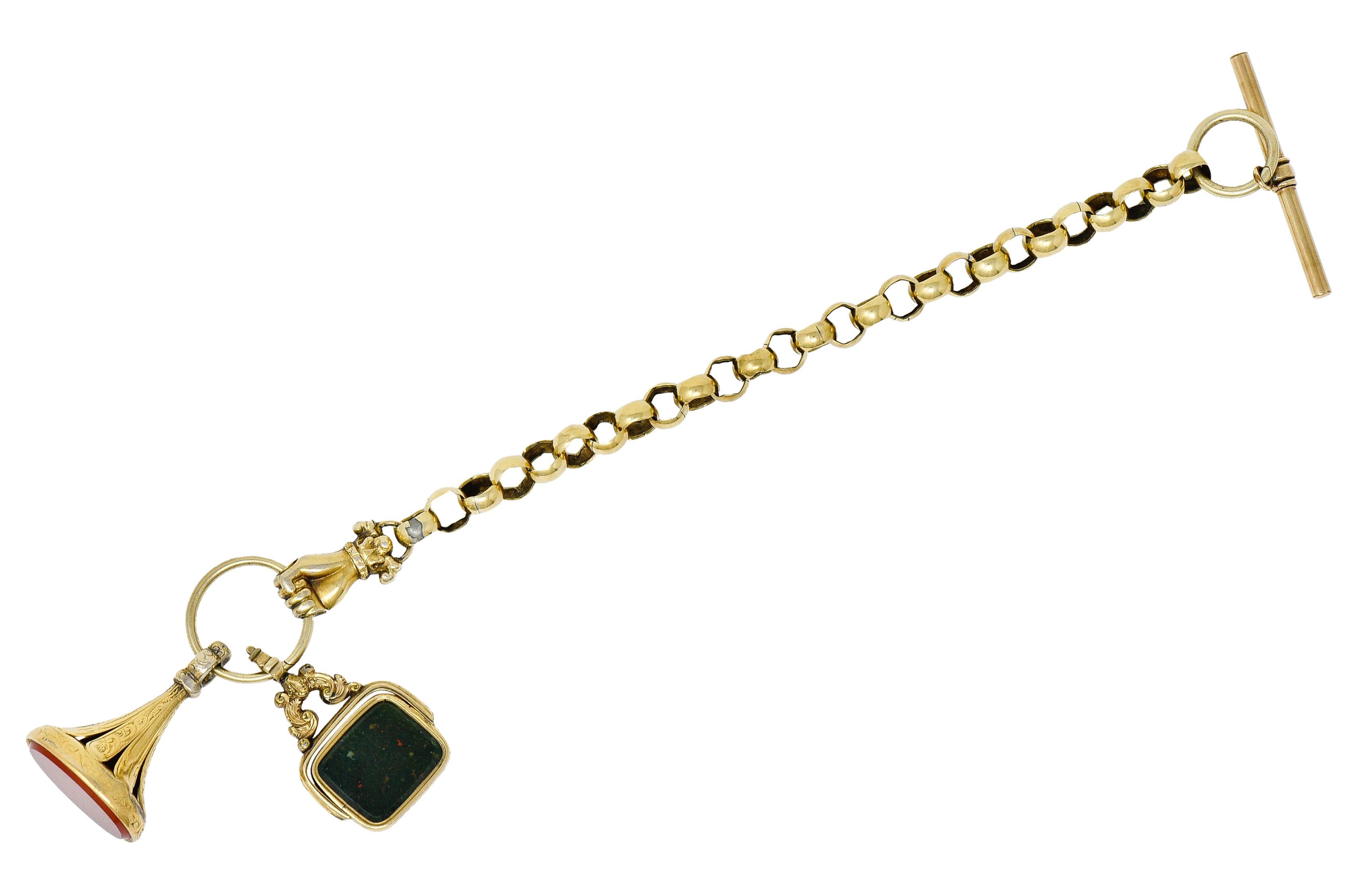 Toggle bracelet is comprised of hand fabricated rolo links

With a highly rendered hand clutching a ring; some wear at knuckles

Ring suspends two substantial fob charms

One features a bezel set and rectangular cushion cut tablet of bloodstone that