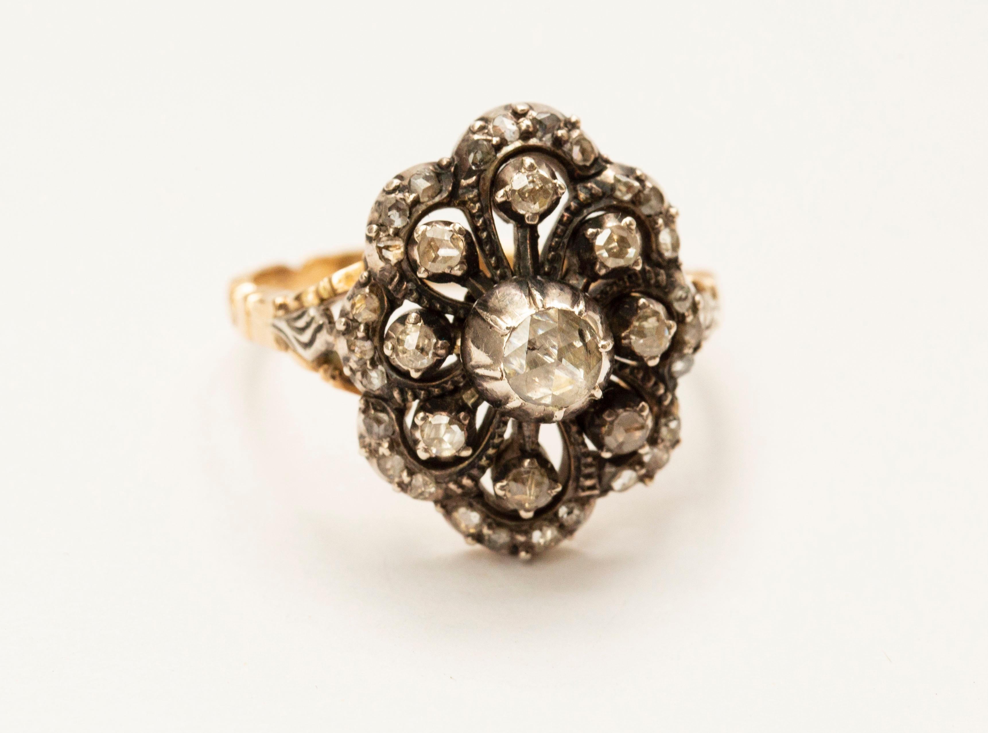 An antique Victorian (ca. 1900) diamond cluster ring /cocktail ring. The ring is made of 14 karat yellow gold and rose cut diamonds (in total 33 diamonds) set in silver foil. The ring features a flower form, and it is suitable to wear during daily