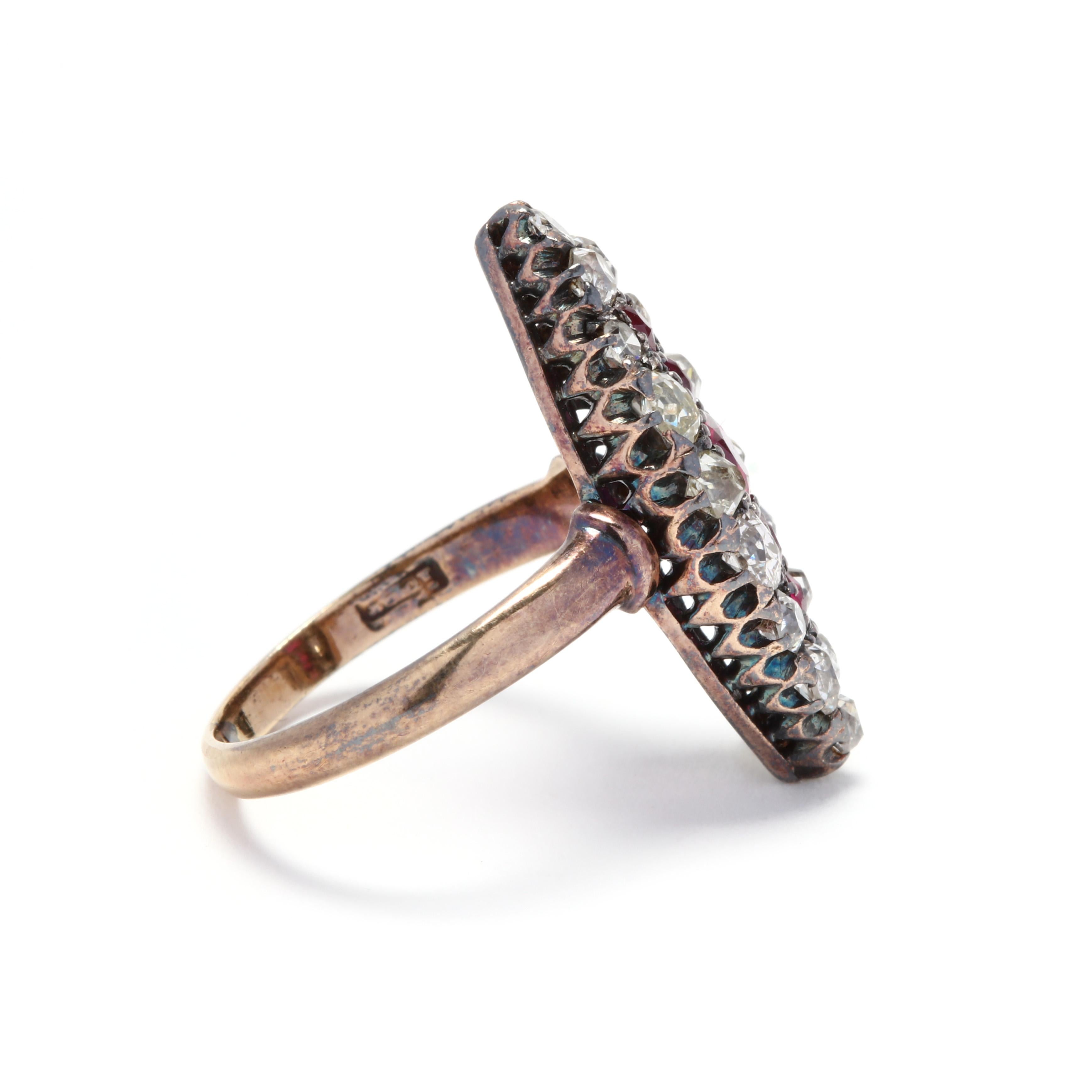 A victorian 14 karat yellow gold, synthetic ruby and diamond navette ring. A lozenge shape centered on a row of synthetic rubies and surrounded by a halo of old European cut diamonds weighing approximately 1 total carat. One replacement diamond is a