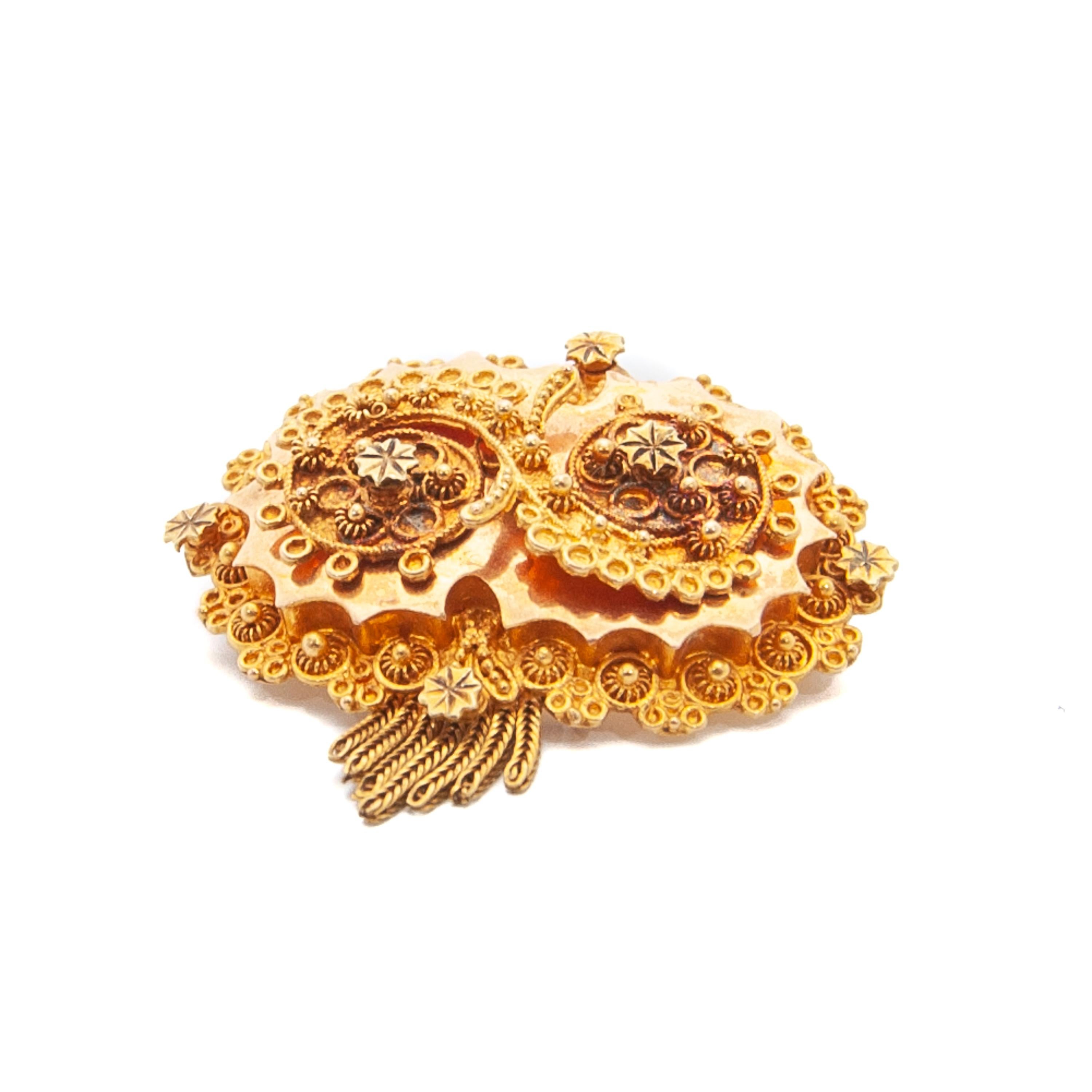 A Victorian 14 karat gold brooch made with cannetille. This ornate brooch has a fine cannetille design with rolled or stamped gold with a raised center piece. The brooch is embellished  with seven gold tassels below the top, this is also called a
