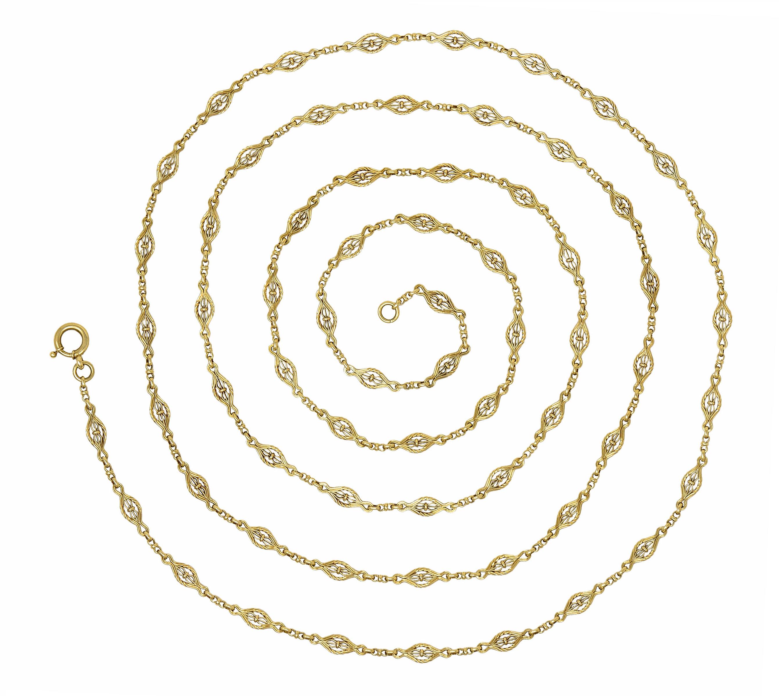 Long chain necklace is comprised of cinched navette links alternating with spacer links

With a ribbed texture and a delicate filigree design

Completed by an oversized spring ring clasp

Tested as 14 karat gold

Circa: 1900

Length: 62 1/2
