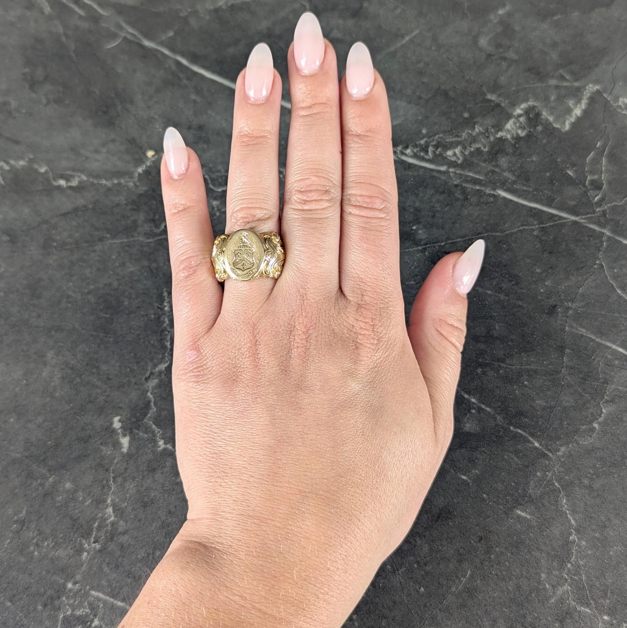 Centering an oval-shaped signet face centering an engraved shield motif
Depicting fleur-de-lis, a griffin head, and inscribed 'Dens Dabit'
Flanked by deeply grooved scroll motif shoulders
Stamped for 14 karat gold
Circa: 1880s
Ring Size: 6 3/4 and