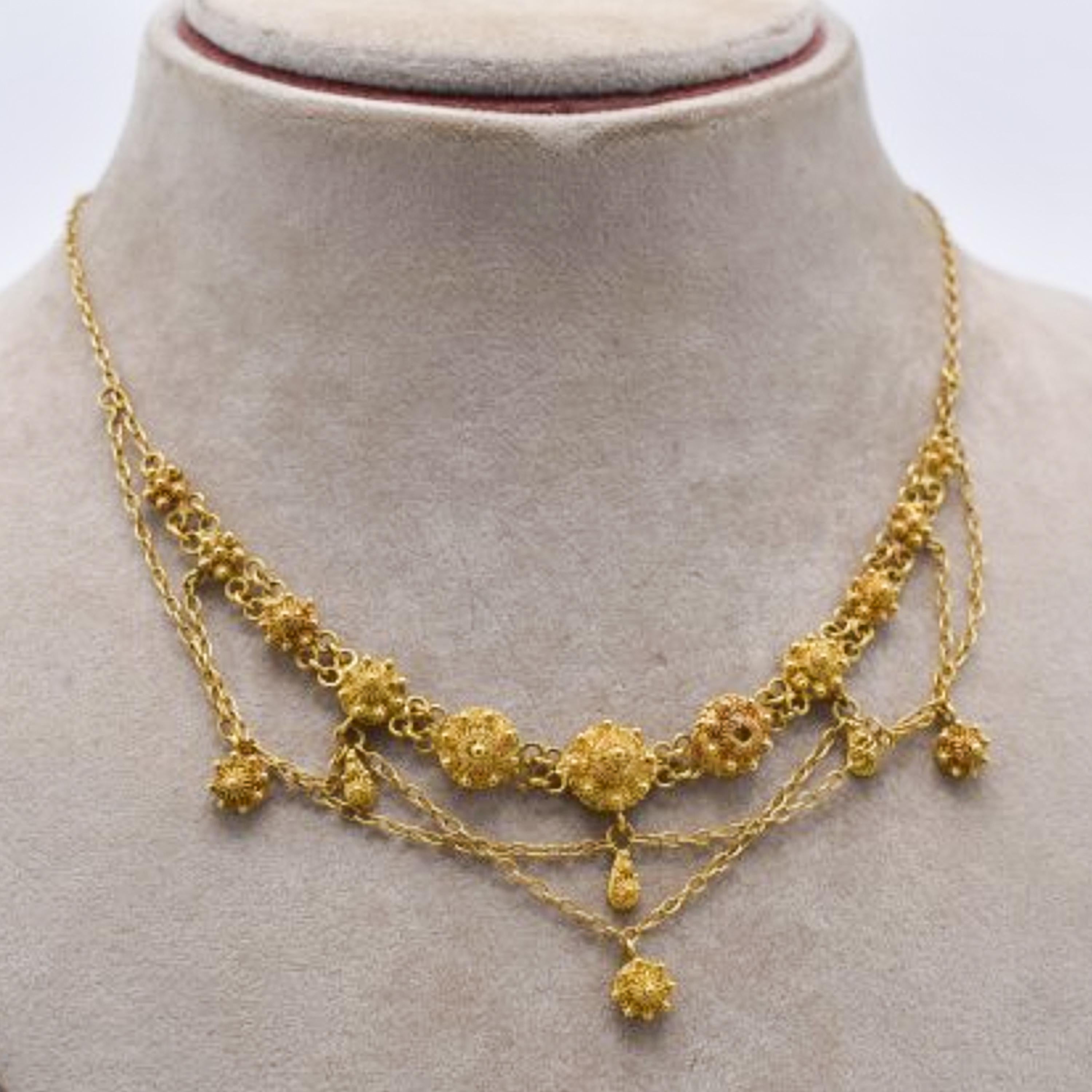 Nineteenth century 14 karat yellow gold chain pendant necklace. The necklace features eleven filigree knots and the chain pendants have six knots in total. This exceptional craftsmanship of the granulation technique, gold wirework twisted scrolls