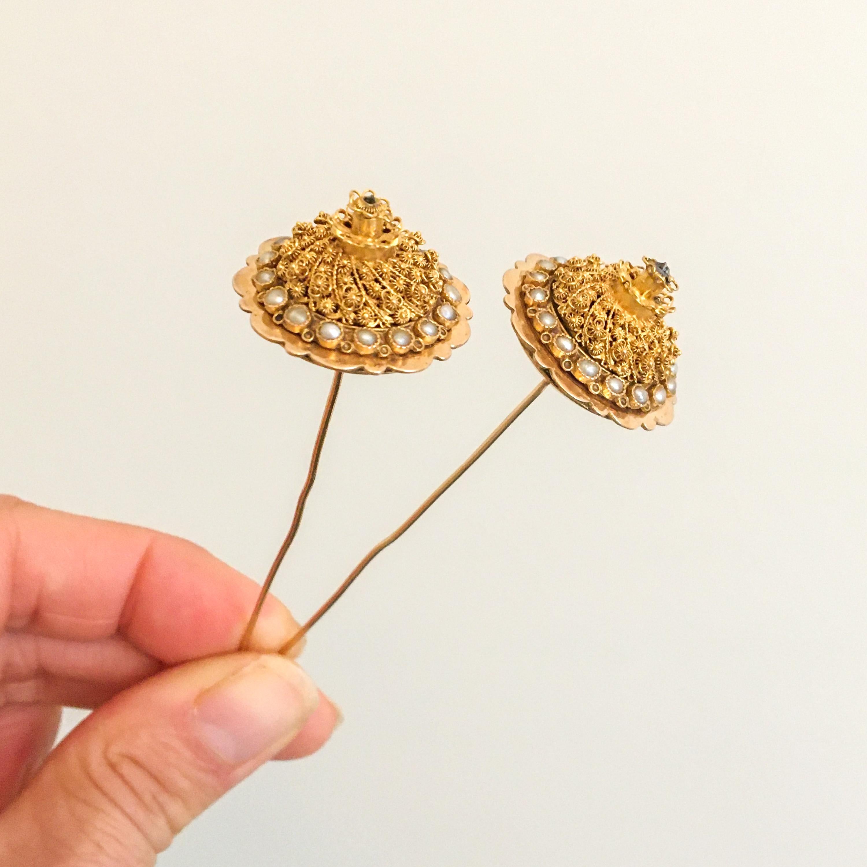 This is a pair of antique 14 karat yellow gold filigree and seed pearl lapel or stick pins. These pearl stick pins, in Dutch called 'tower pins', feature seventeen bright seed pearls. Each pin is decorated with cannetille and fine filigree, while