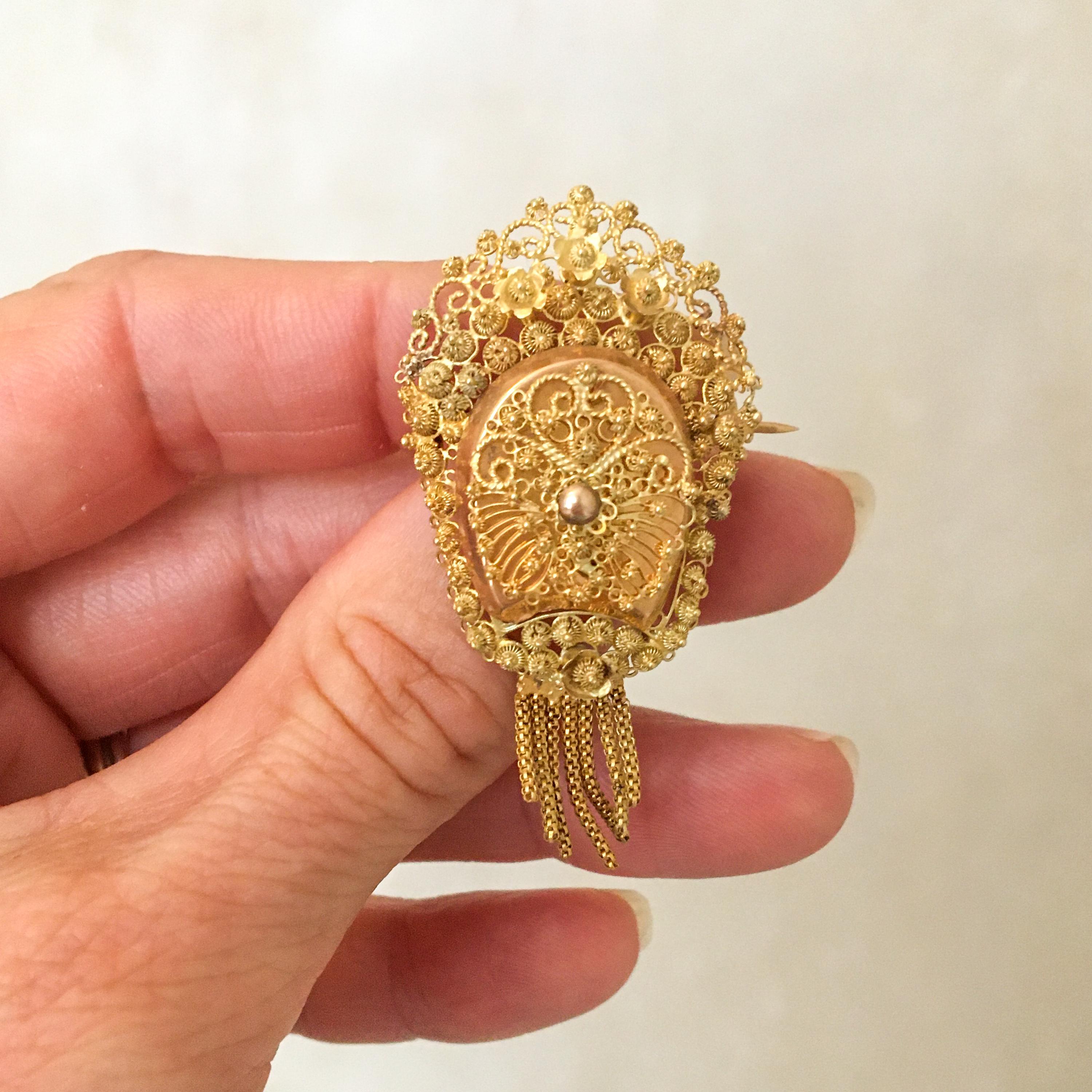 This is an antique 19th century 14 karat yellow gold tassel brooch created with fine filigree and cannetille work. The brooch is skillfully handcrafted and gives the impression of lace or embroidery. The cannetille work on this brooch is a very