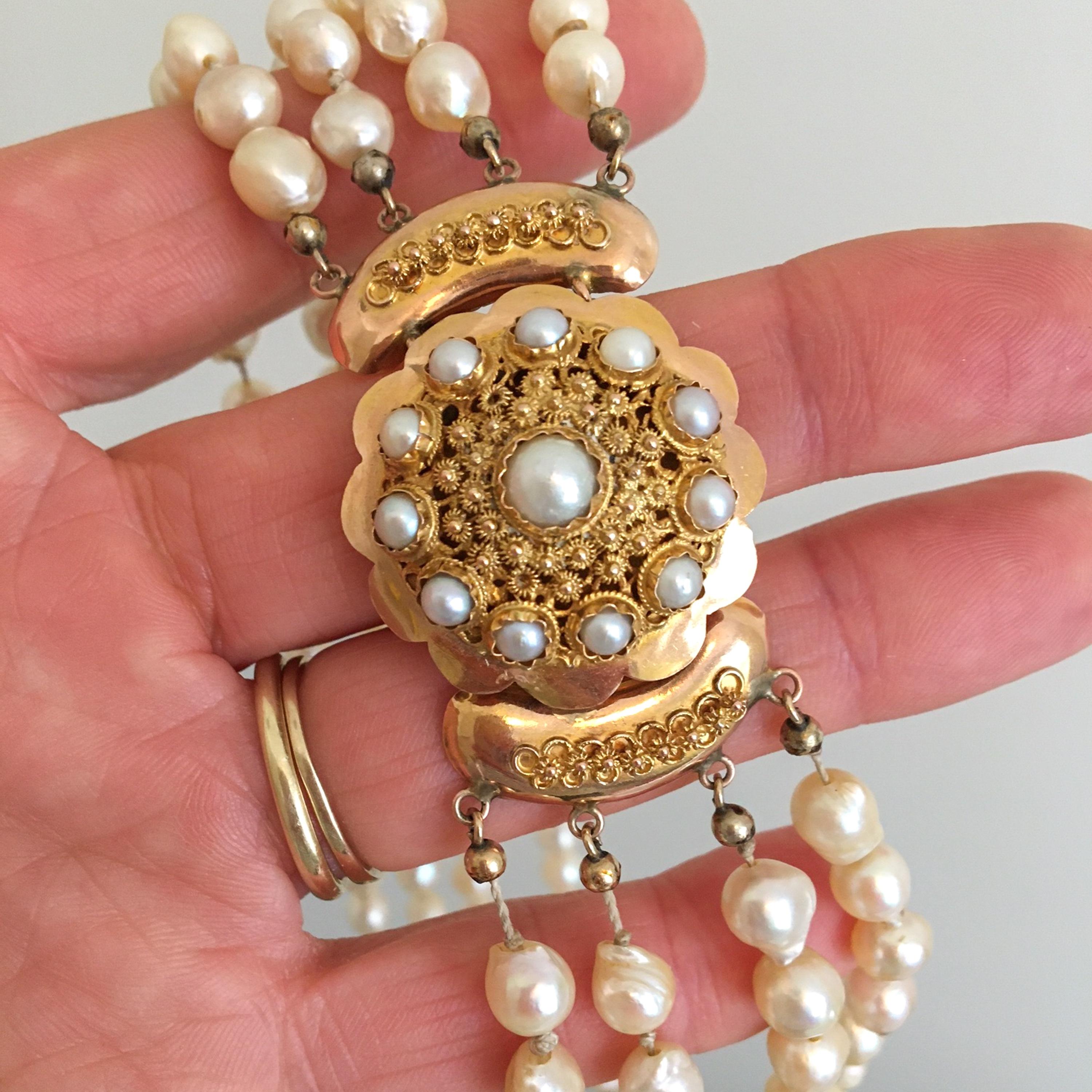 A freshwater cultured pearl necklace set with a round 14 karat gold clasp. The clasp consists of twelve clear cultured pearls surrounded by very fine filigree. The ornate clasp has rope motifs around the pearls and a beautifully scalloped border.