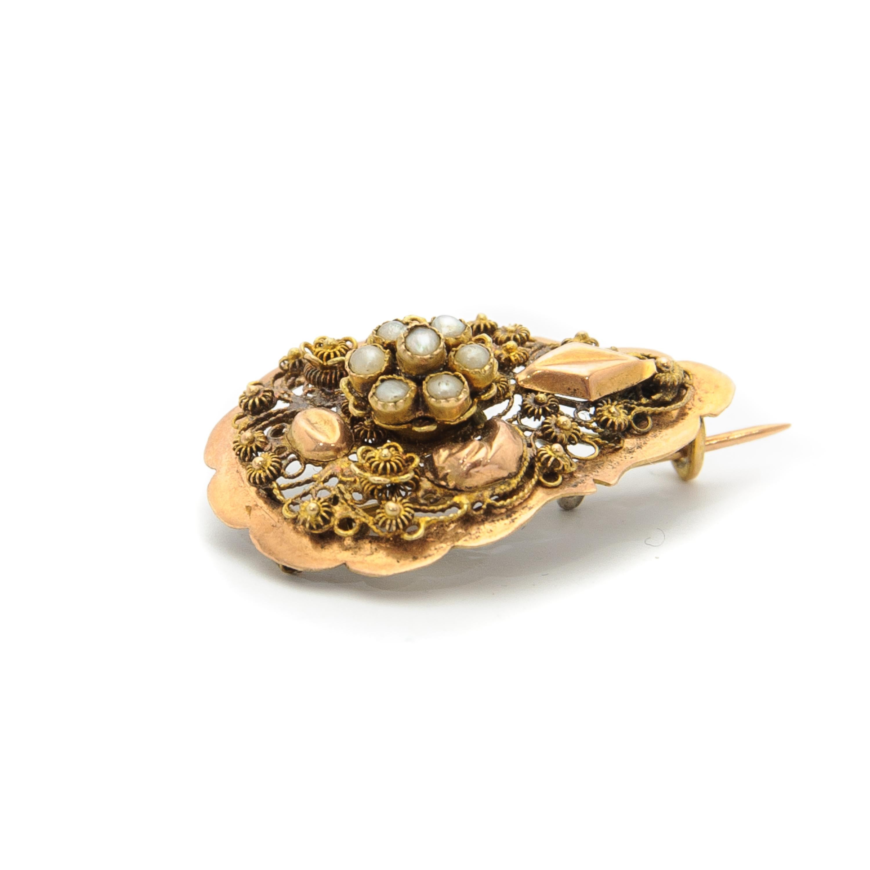 An antique 19th century drop-shaped brooch created in 14 karat gold. The brooch is set with seven seed pearls and the surface is beautifully detailed with fine filigree and cannetille work. Cannetille typically features fine gold wires or thinly