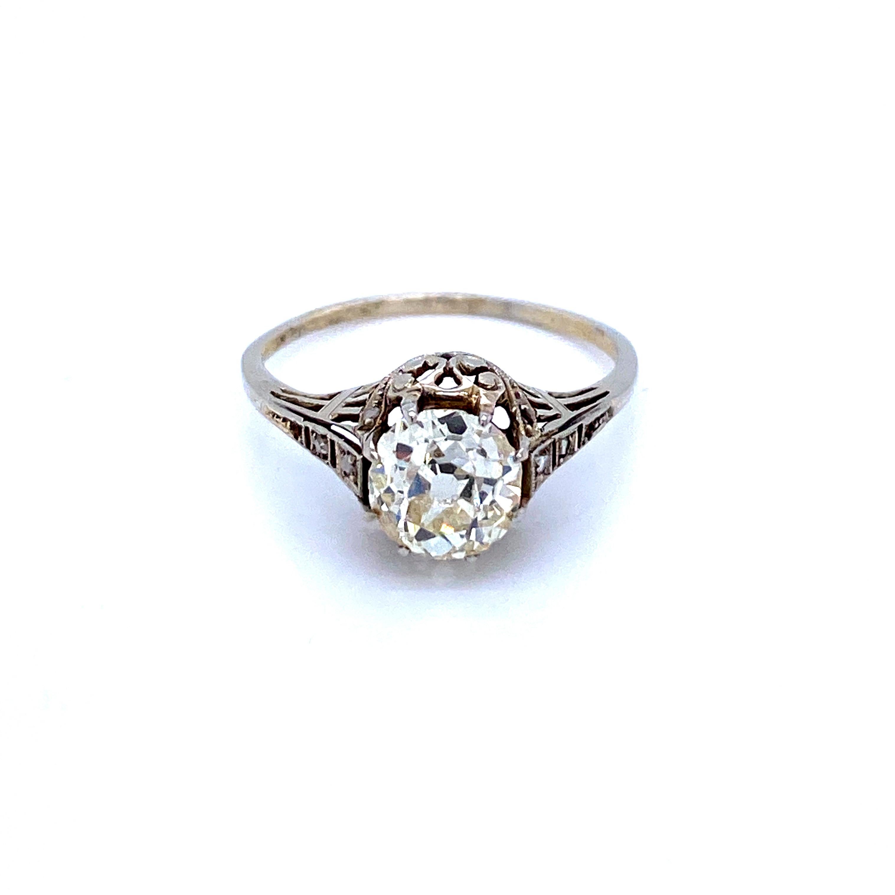  This stunning antique solitaire engagement ring set in 18k white gold is centered with a prominent old-mine cut diamond of 1.40 ct, K color and SI2 clarity. 
The pierced decorated shoulders are embellished with a textured design and small rose-cut