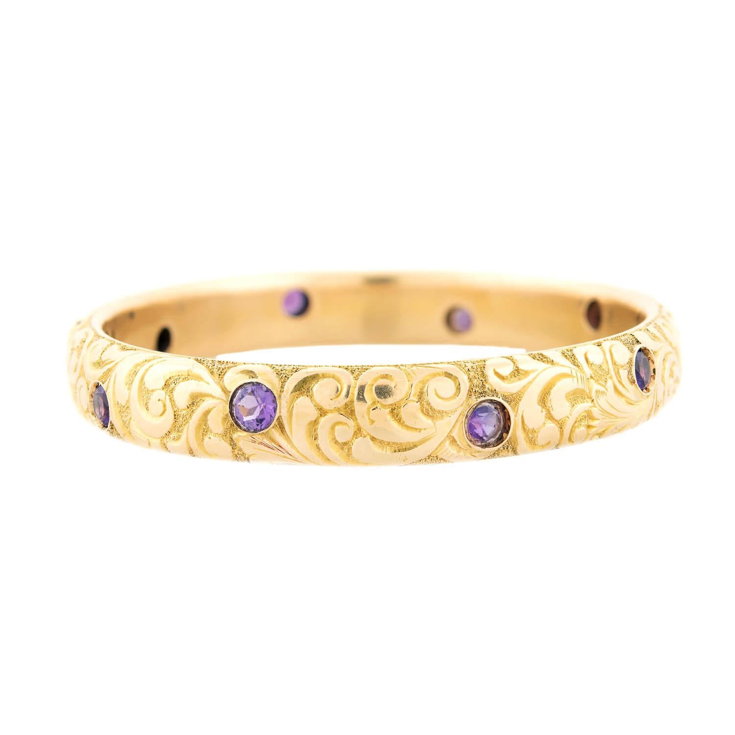 A beautiful gold and amethyst bangle bracelet from the Art Nouveau (ca1900) period! This stunning 14kt gold bracelet features a carved scrolling design that carries around the entire outer surface of the bracelet, adding wonderful texture and depth.