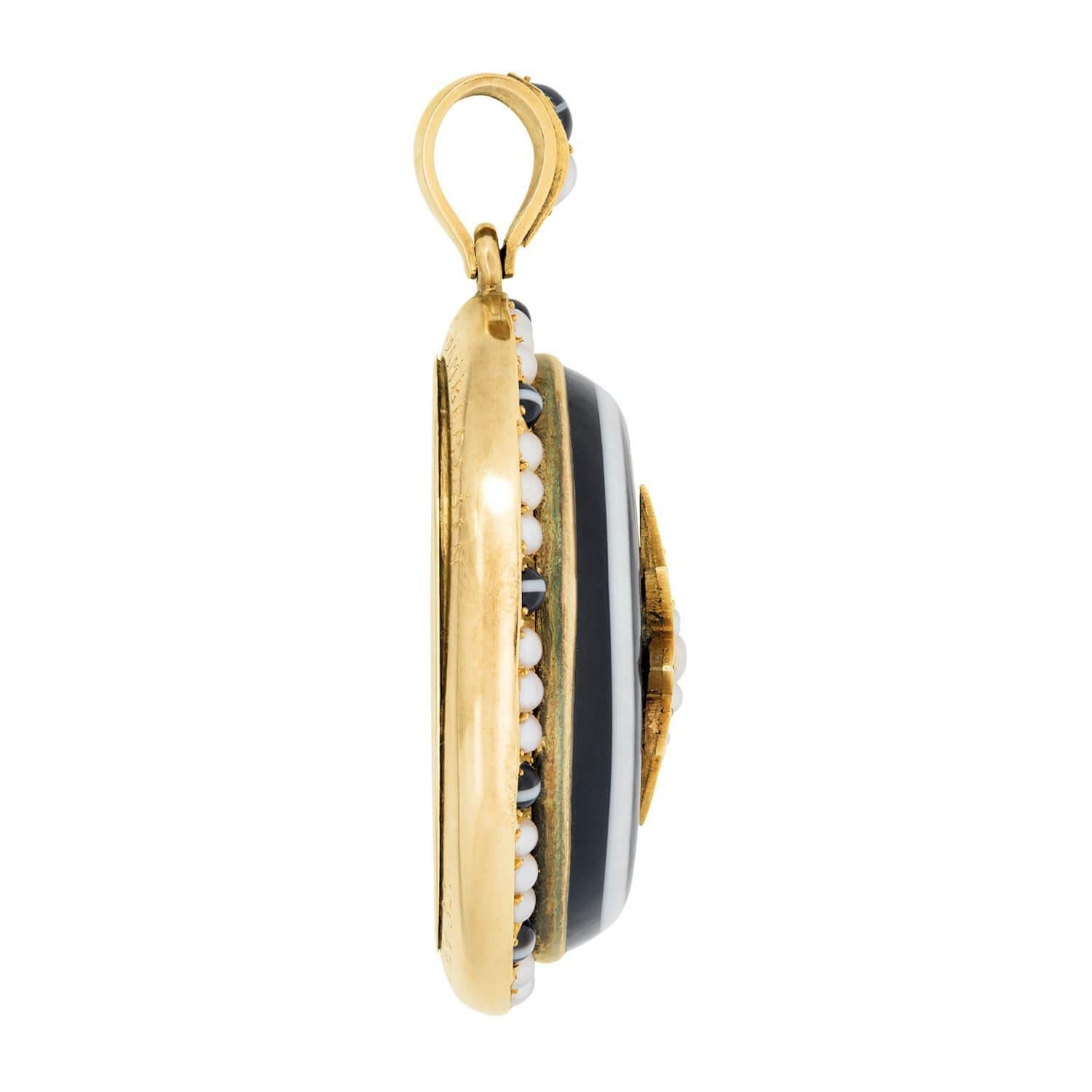 Un bellissimo medaglione/pendente in agata a bande di epoca vittoriana (ca. 1850)! Realizzato in oro 14 carati, il pezzo di forma ovale incornicia una pietra di agata a bande al centro, di colore marrone intenso con una striscia di bianco crema. Al