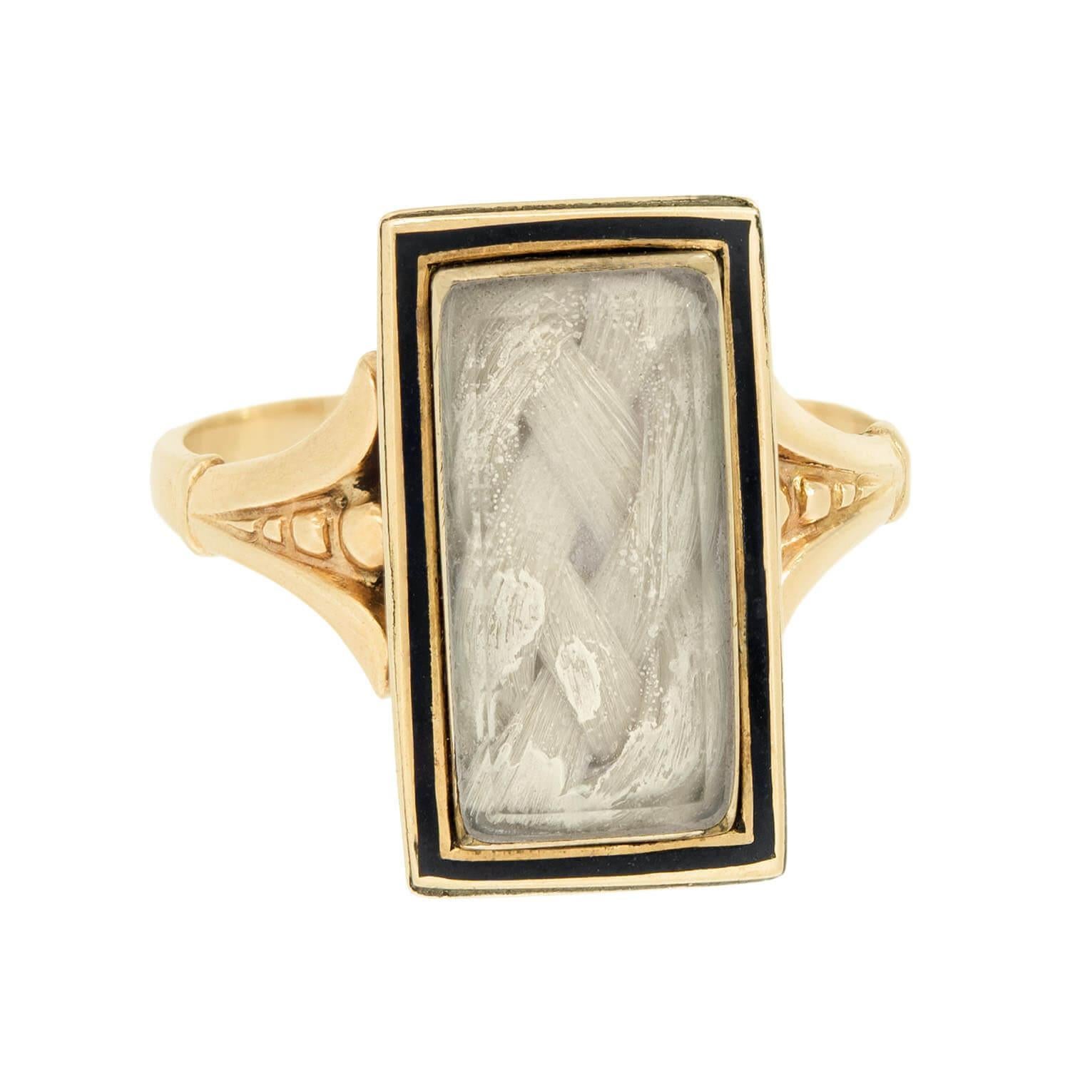 A unique mourning ring from the Victorian (ca1880s) era! Crafted in 14k yellow gold, this ring features a rectangular-shaped centerpiece, which features a thin black enamel border. The centerpiece features a lock of blonde hair, which is woven into