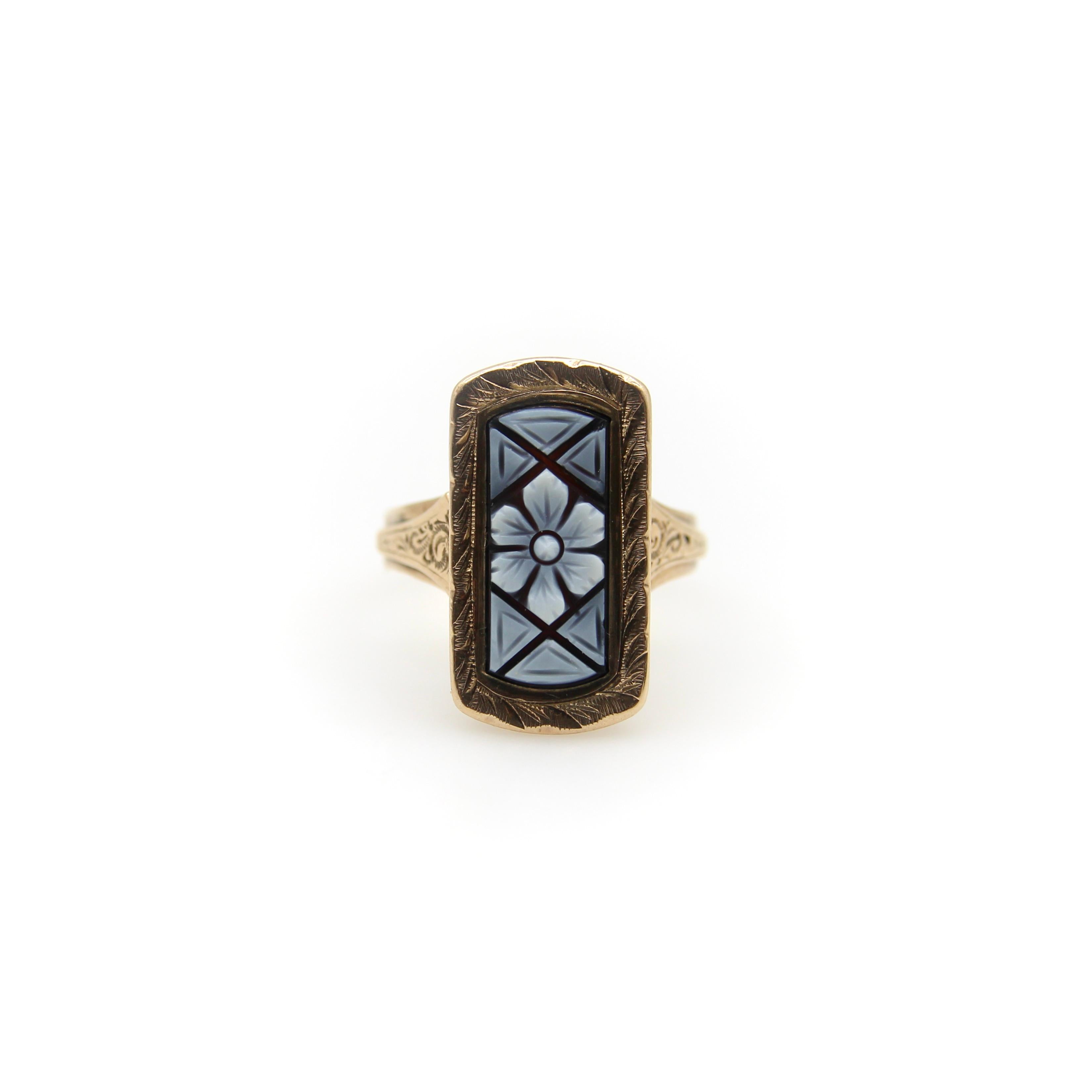This Victorian 14k gold ring features a beautiful elongated panel carved from a black and white banded agate. The central feature is a flower, with the white agate defining the petals. Geometric shapes carved out of the rest of the panel draw the