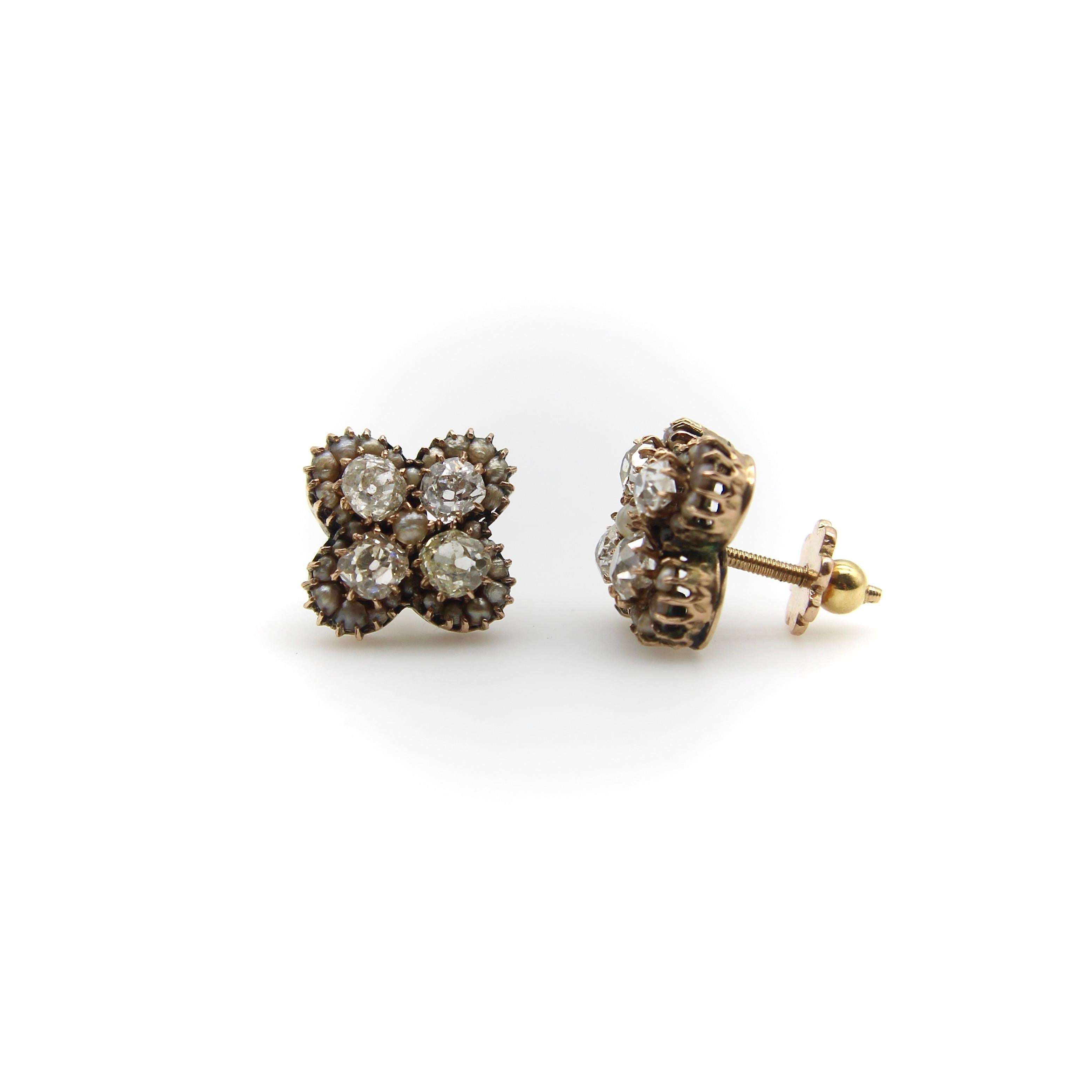 These 14k gold diamond and pearl earrings are from the Early Victorian era, circa the 1860’s. They contain eight cushion-shaped Old Mine Cut diamonds surrounded by pearls, all prong set into a quatrefoil shape reminiscent of a clover. Because they