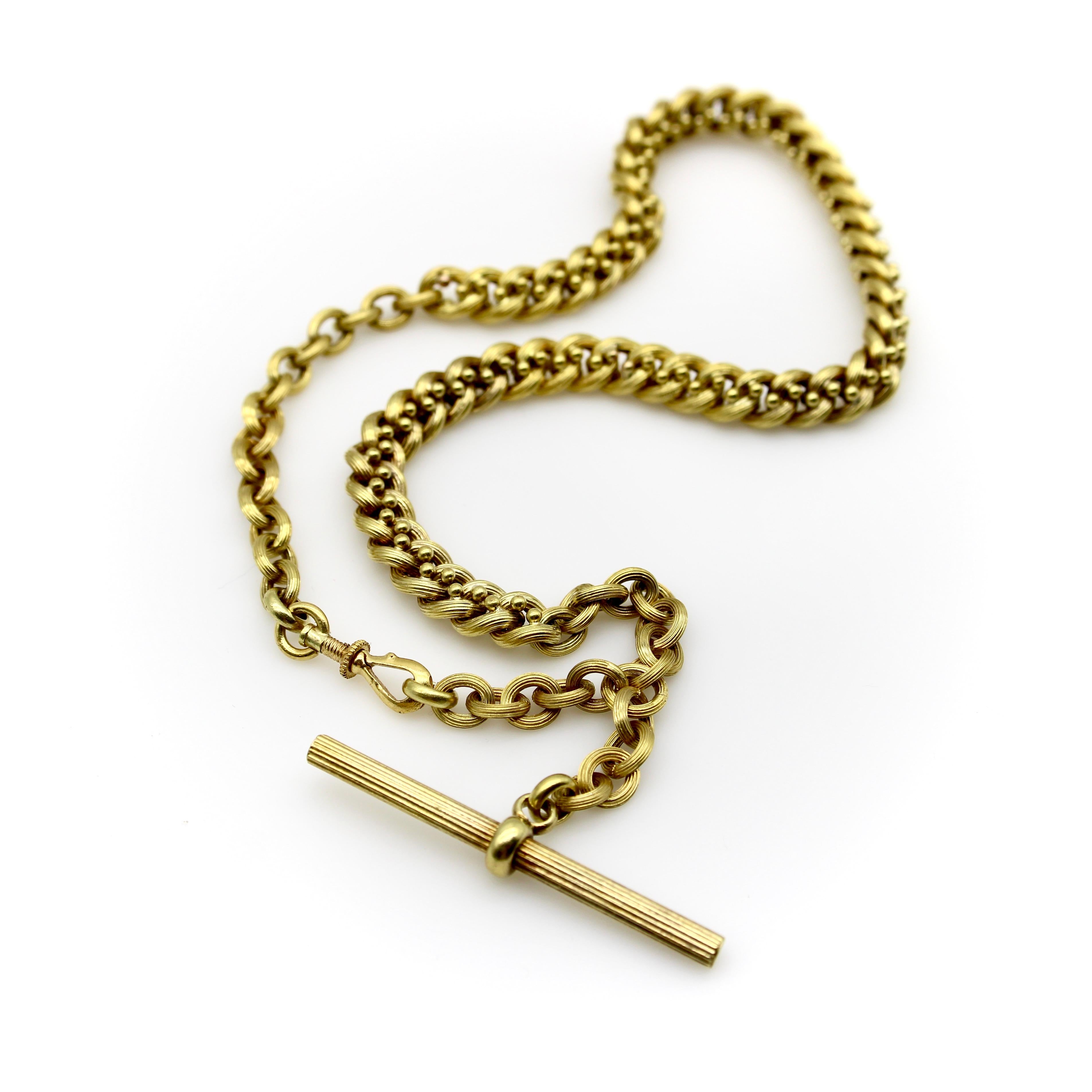 This 14k gold watch chain has a fabulous hollow link interwoven with tiny balls for an unusual variation of a curb link. The links are carved with a ribbed texture that give a matte surface to the gold. This creates a unique visual texture that
