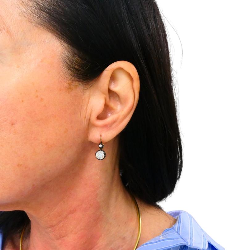 Questo paio di orecchini vittoriani con due pietre e diamanti è realizzato in oro giallo 14k con montatura in argento. Ogni orecchino è progettato con un piccolo diamante superiore e un diamante più grande sospeso sotto, creando una classica