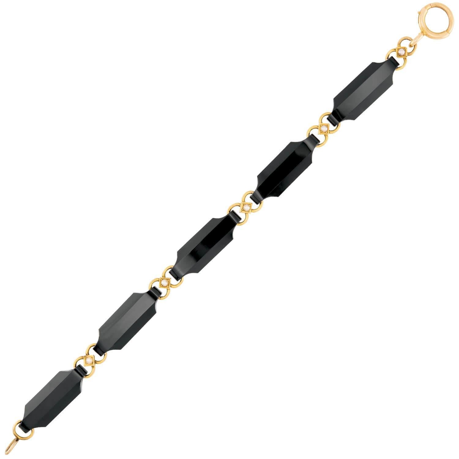 A simply stunning onyx and pearl link bracelet from the Victorian (ca1880s) era! Crafted in 14k yellow gold, this piece is comprised of 5 oblong faceted onyx links. The onyx stones display a breathtaking black hue, which wonderfully complements the