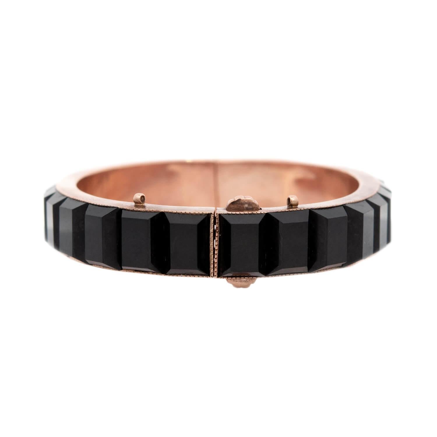 A gorgeous bangle bracelet from the Victorian (ca1880) era! The bracelet is crafted in 14k rose gold, and has a simple, yet very stylish design. On the front of the bracelet is a single row of faceted onyx stones in a channel setting. The onyx