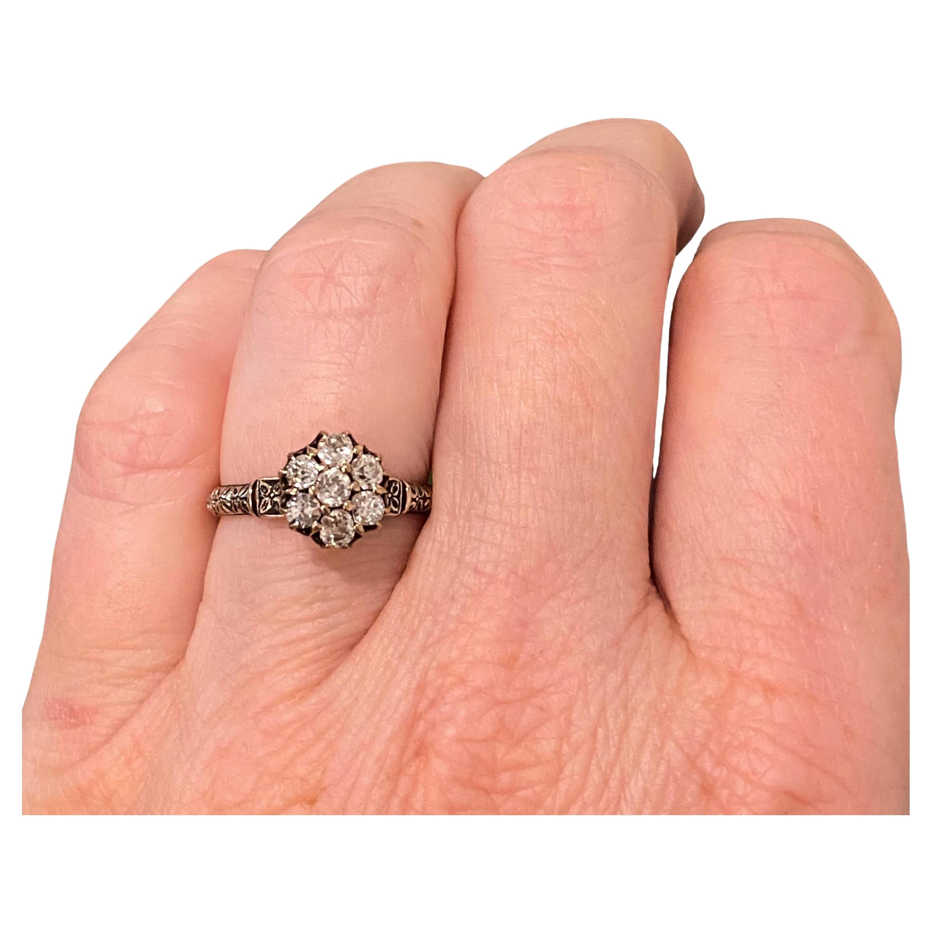 Bague ancienne en or rose 14 carats, présentant une grappe de sept diamants sertis dans un panier en forme de couronne, soutenue par des épaulements gravés à la main.
7 diamants taillés à l'ancienne : 0,70ctw. Couleur : H-I, Clarté : SI1-I1
Mesures