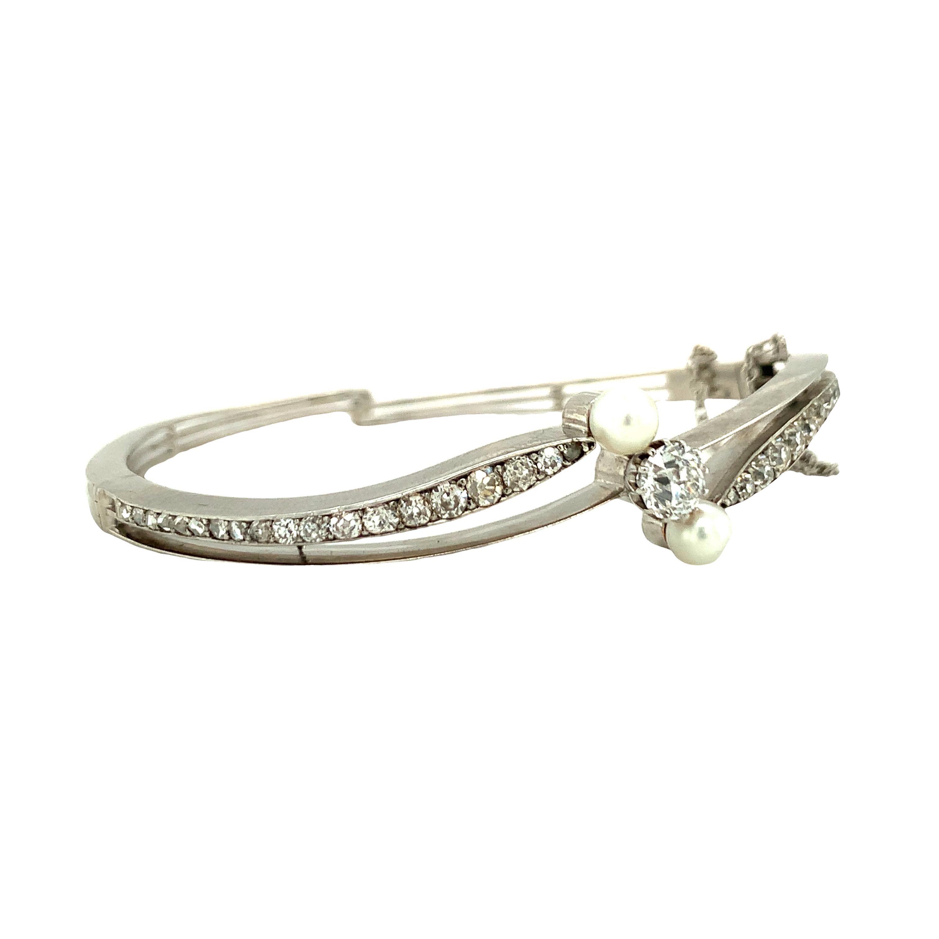 One Victorian 14K white gold diamond and pearl bangle bracelet featuring 29 old European cut diamonds totaling 0.80 ct. with J-K color and SI-2 clarity.  Two white cultured round pearls measuring 4.5 mm. in diameter each.  Bracelet measures 15 mm.