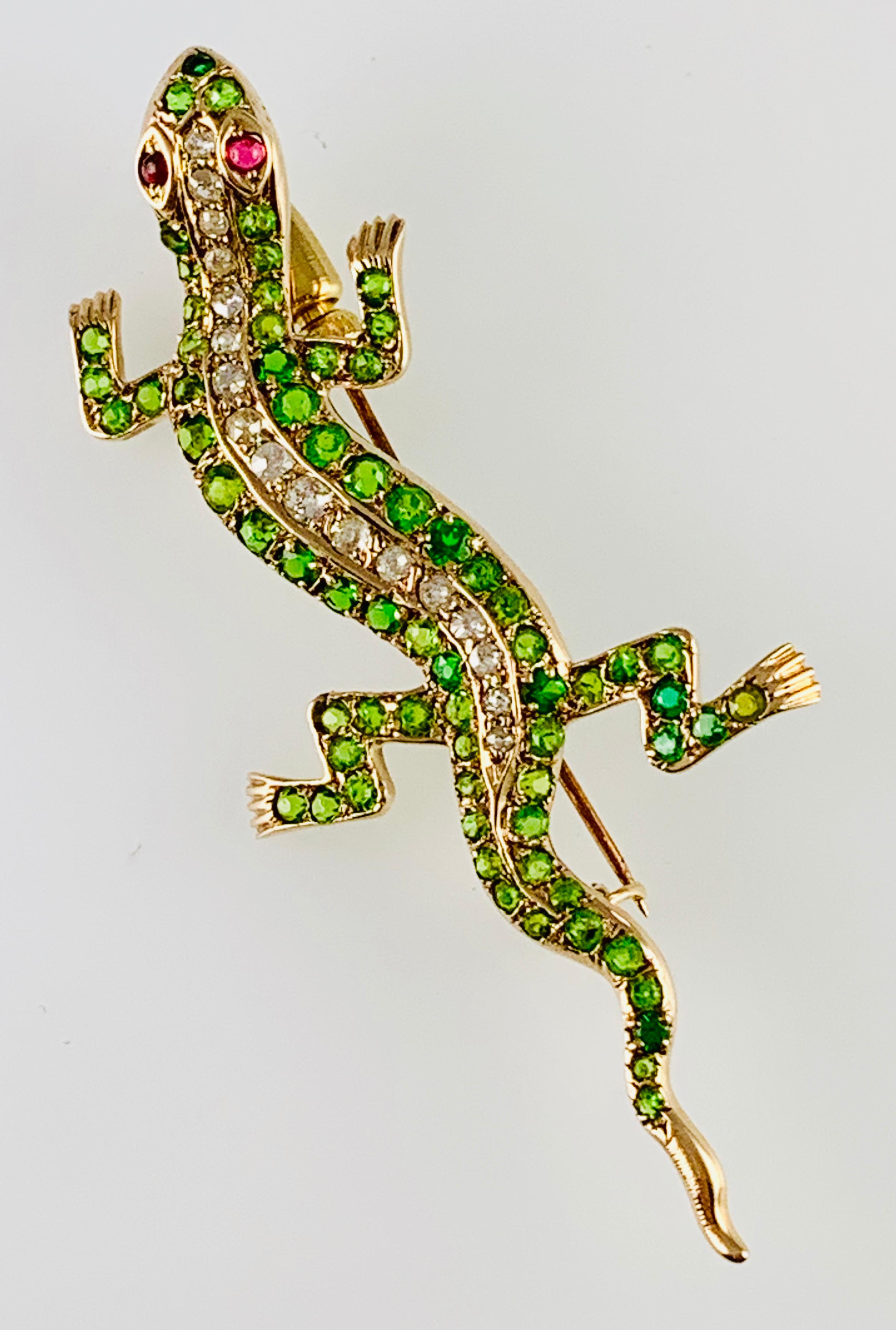 Gorgeous Victorian Diamond & Tsavorite Garnet Lizard Brooch! It is made in 14K Yellow Gold and contains 17 European Cut Round Diamonds accented by pave back tsavorite Garnets as well as Ruby eyes. It m measures 2.5 inches long by 1&1/8 inches wide