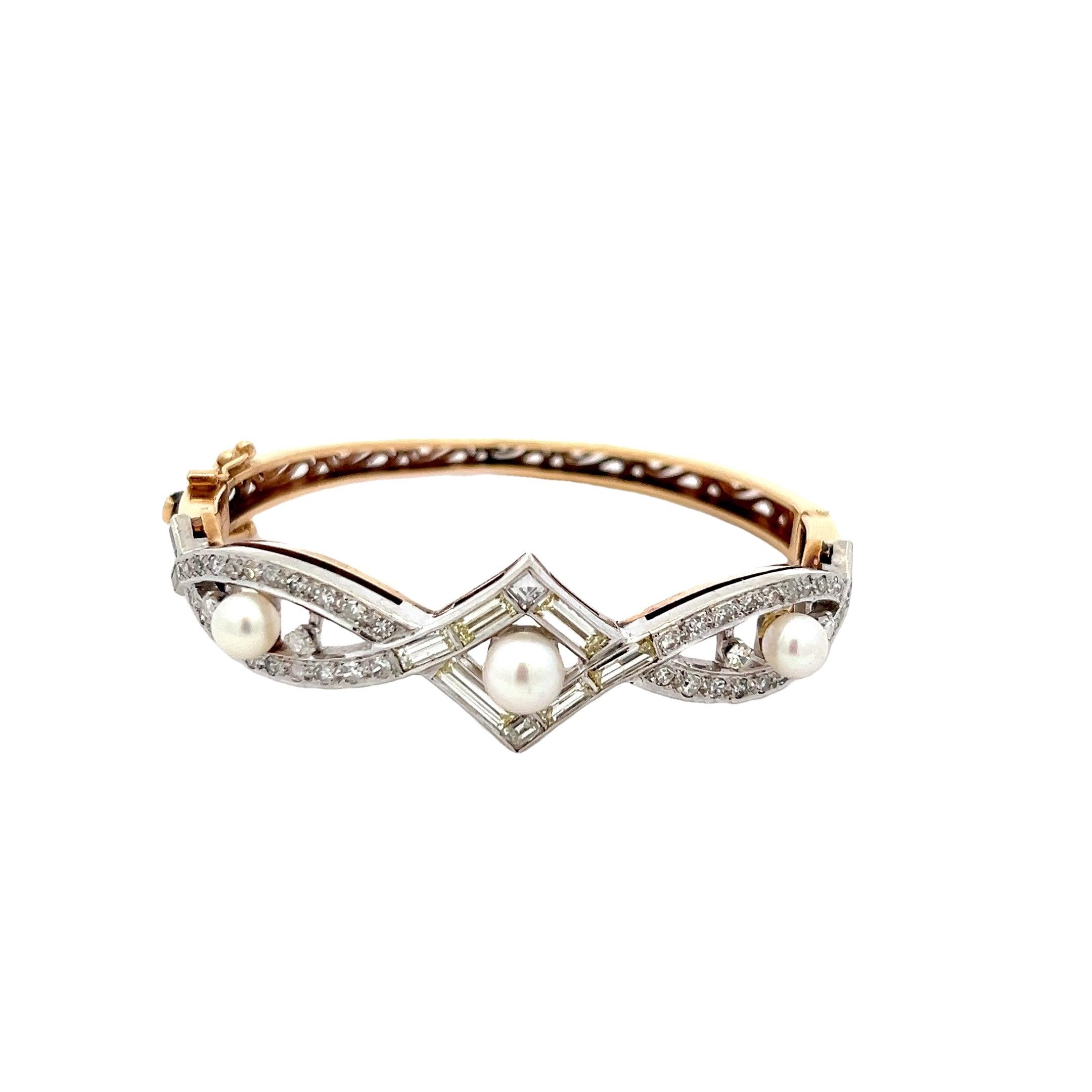 A graceful example of Victorian-era elegance, this antique bangle bracelet is crafted in 14K yellow gold with platinum-topped settings. Its ornate, openwork design showcases three lustrous cultured pearls nestled within a curving diamond-set