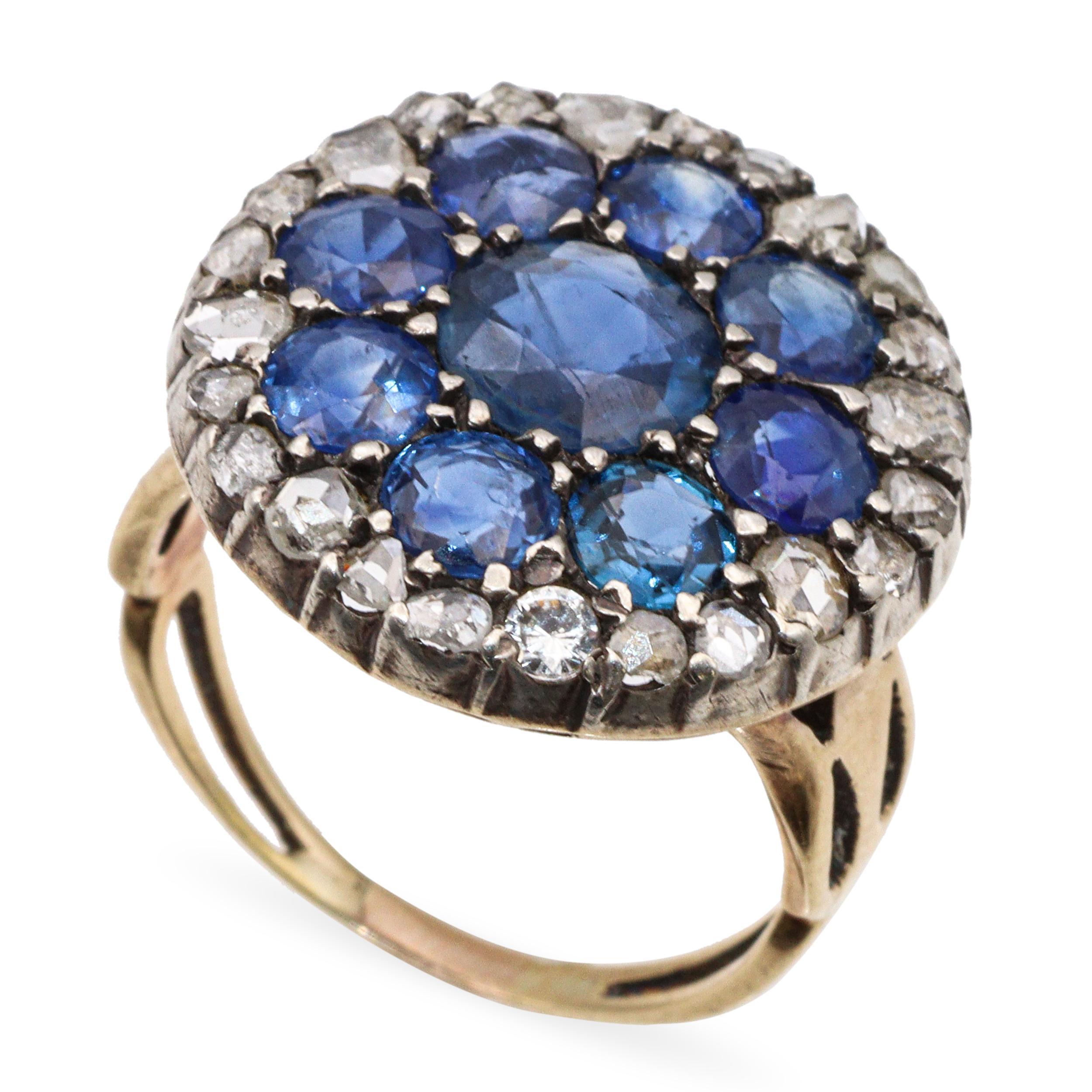 Magnifique exemple du design du milieu de l'époque victorienne, cette bague ancienne présente un saphir de Birmanie central de 6,75 mm non chauffé, entouré d'une grappe vibrante de huit saphirs de 4 mm non chauffés (très probablement également de