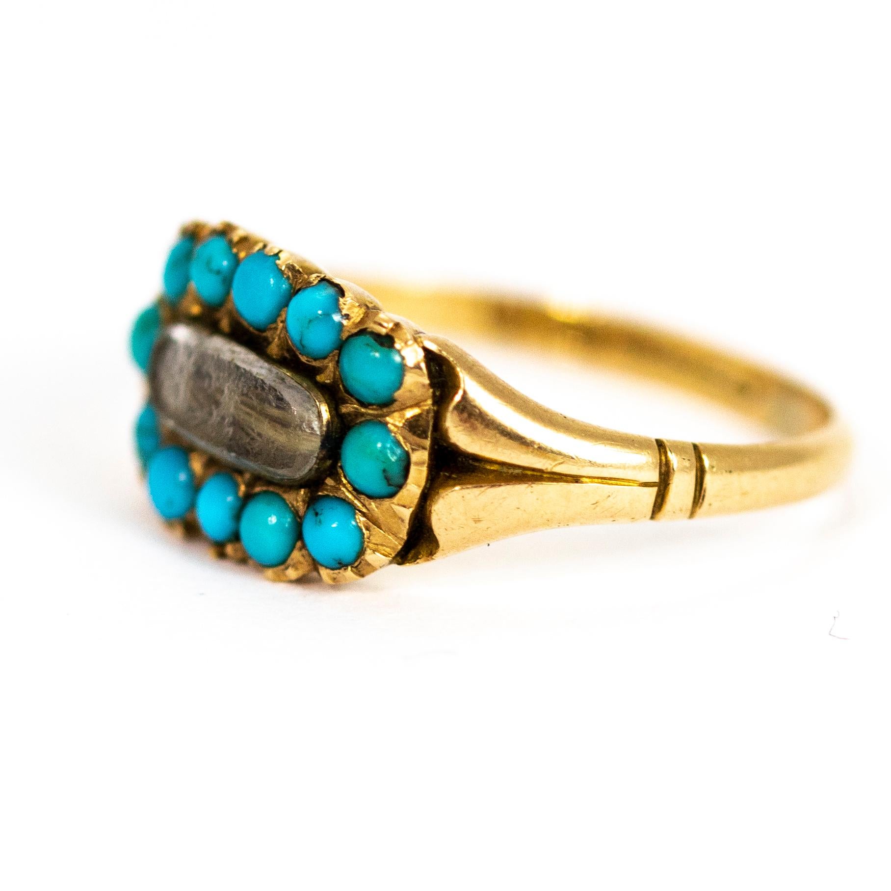 A stunning antique Victorian mourning ring. Fronted with a glazed locket compartment containing woven hair, surrounded by a halo of beautiful round turquoise cabochons. Modelled in 15 carat yellow gold. Fully hallmarked 1886 Birmingham,