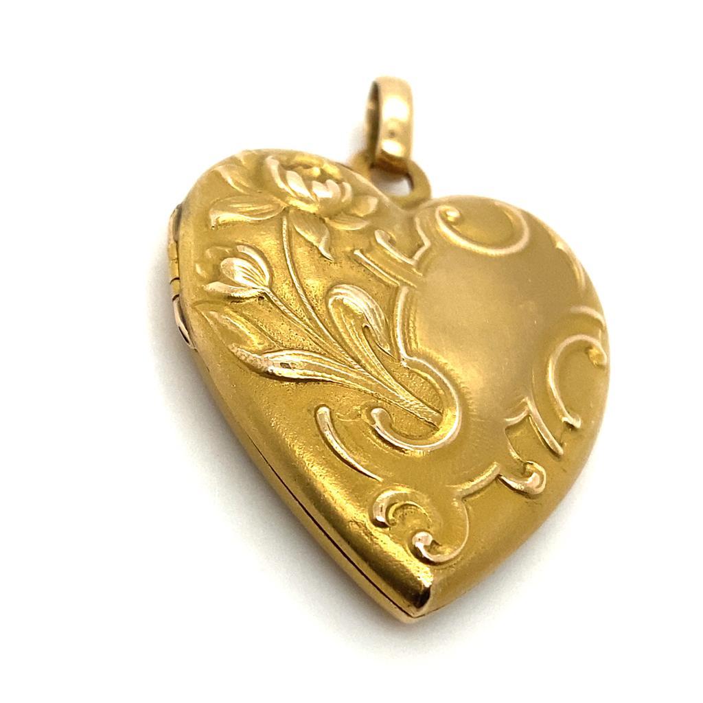 A Victorian 15 karat yellow gold heart shaped locket pendant.

This sweet heart shaped locket features an ornate raised foliate design heart, is hinged and memorial glass is trimmed to fit inside one of the heart halves.

The chain the pendant is