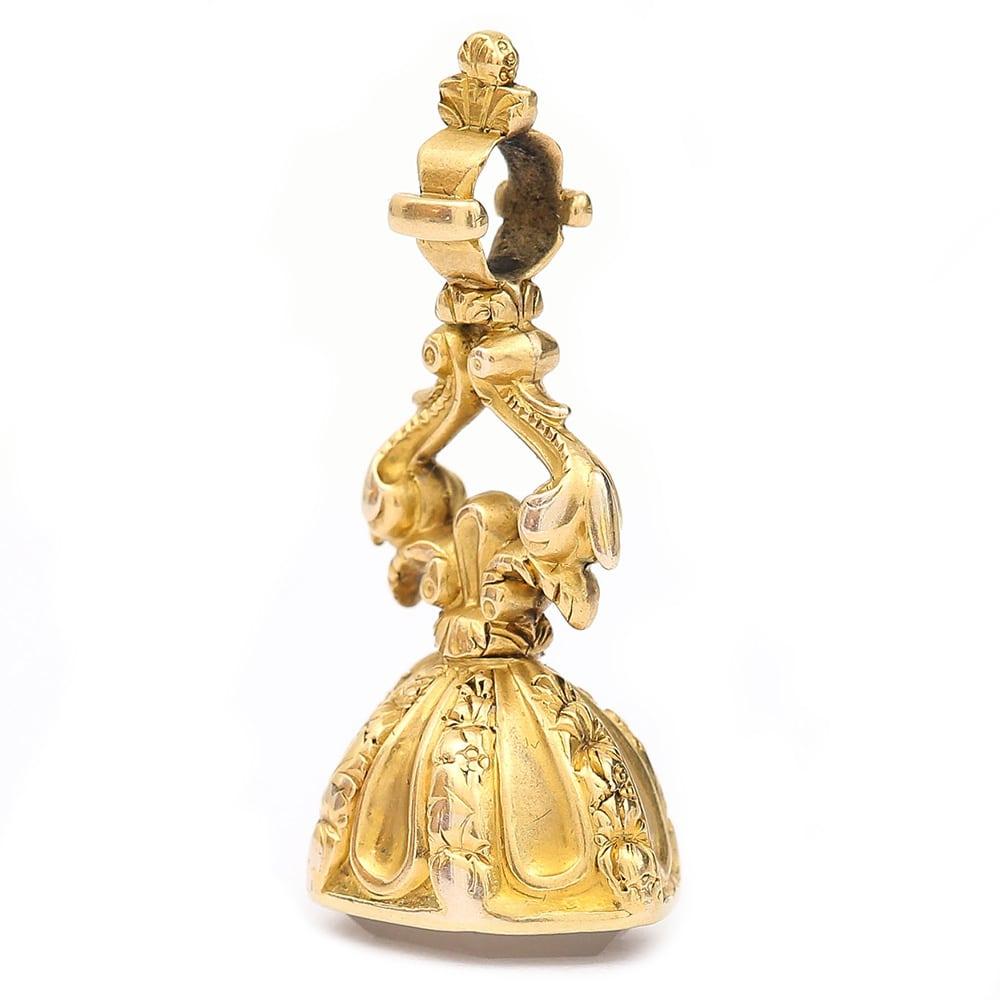 A fancy 15 karat yellow gold ornate scroll seal fob with a’ blind’ white faceted quartz base. This is a design that was prominent in the Georgian period but also was most likely manufactured during the Victorian era. With a large bale at the top of