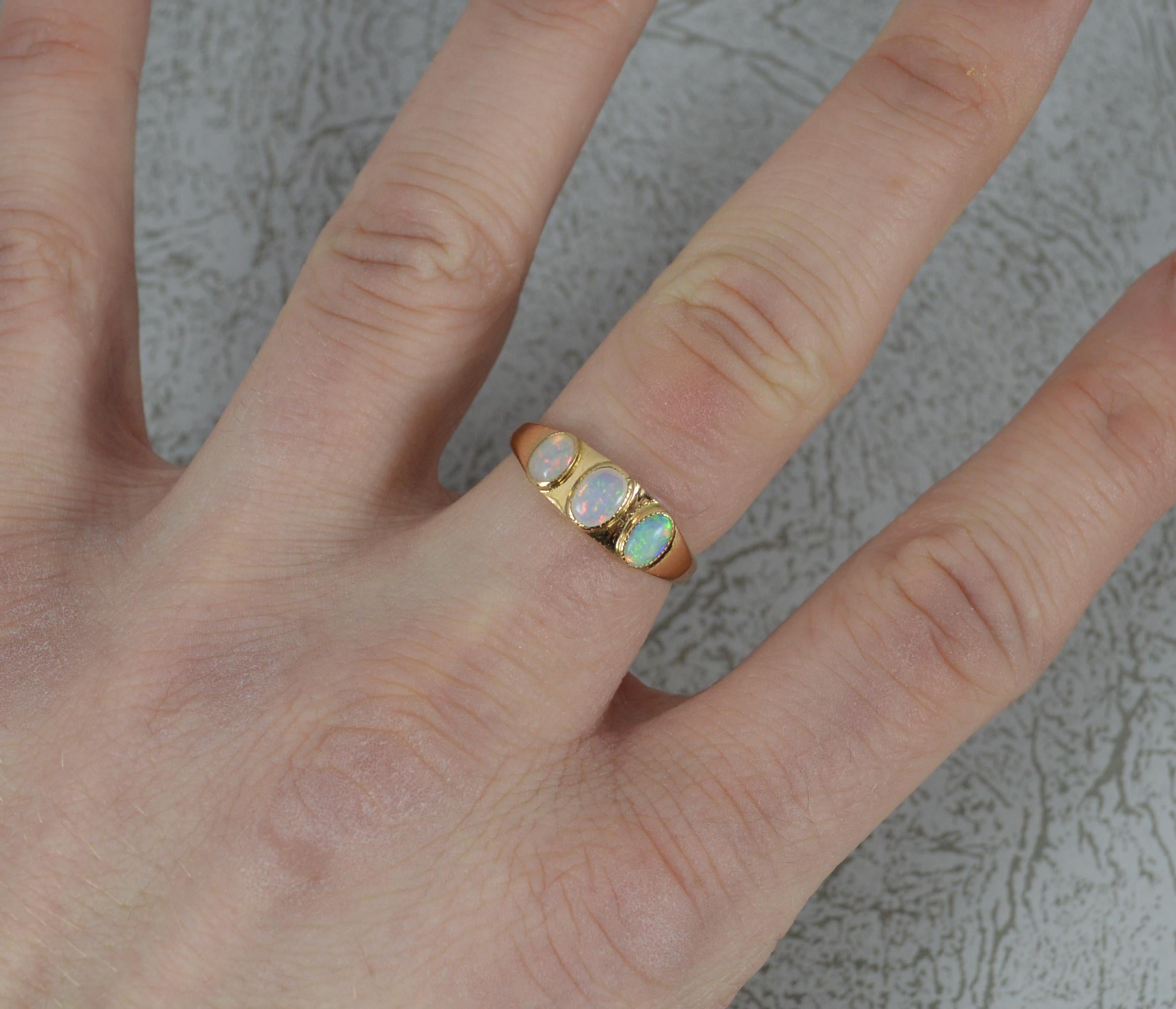 A late Victorian period three opal ring.
Solid 15 carat yellow gold example.
Designed with three natural oval shaped opals in fine bezel settings.
3.8mm x 5.4mm central opal.
13.5mm spread of stones. 5.9mm wide band to front.

CONDITION ; Excellent.