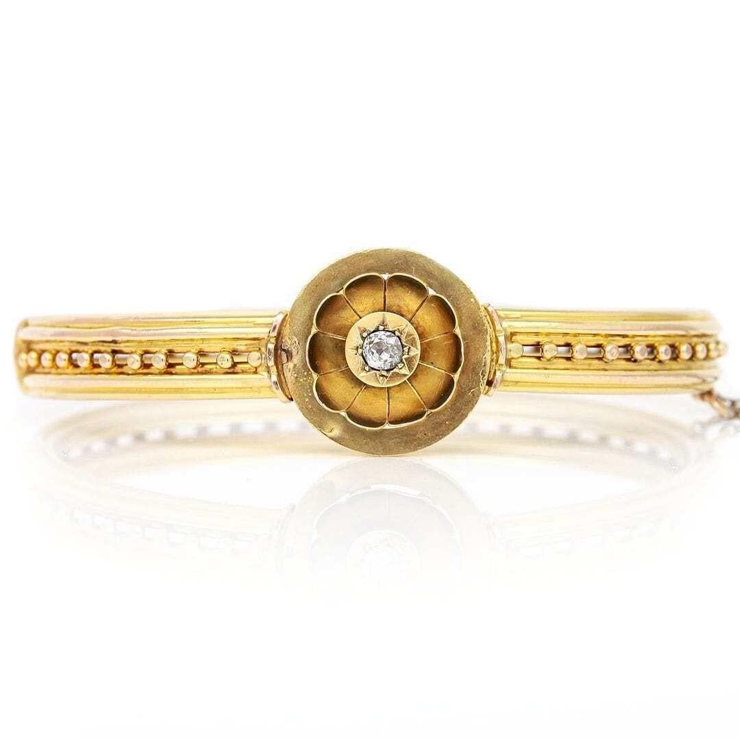 A beautiful Victorian 15ct yellow gold Old Mine Cut diamond floral head hinge bangle dating from circa 1870. A fine example of antique craftsmanship the bangle has a 0.10ct diamond set gold petalled flower head with all its petals remaining intact