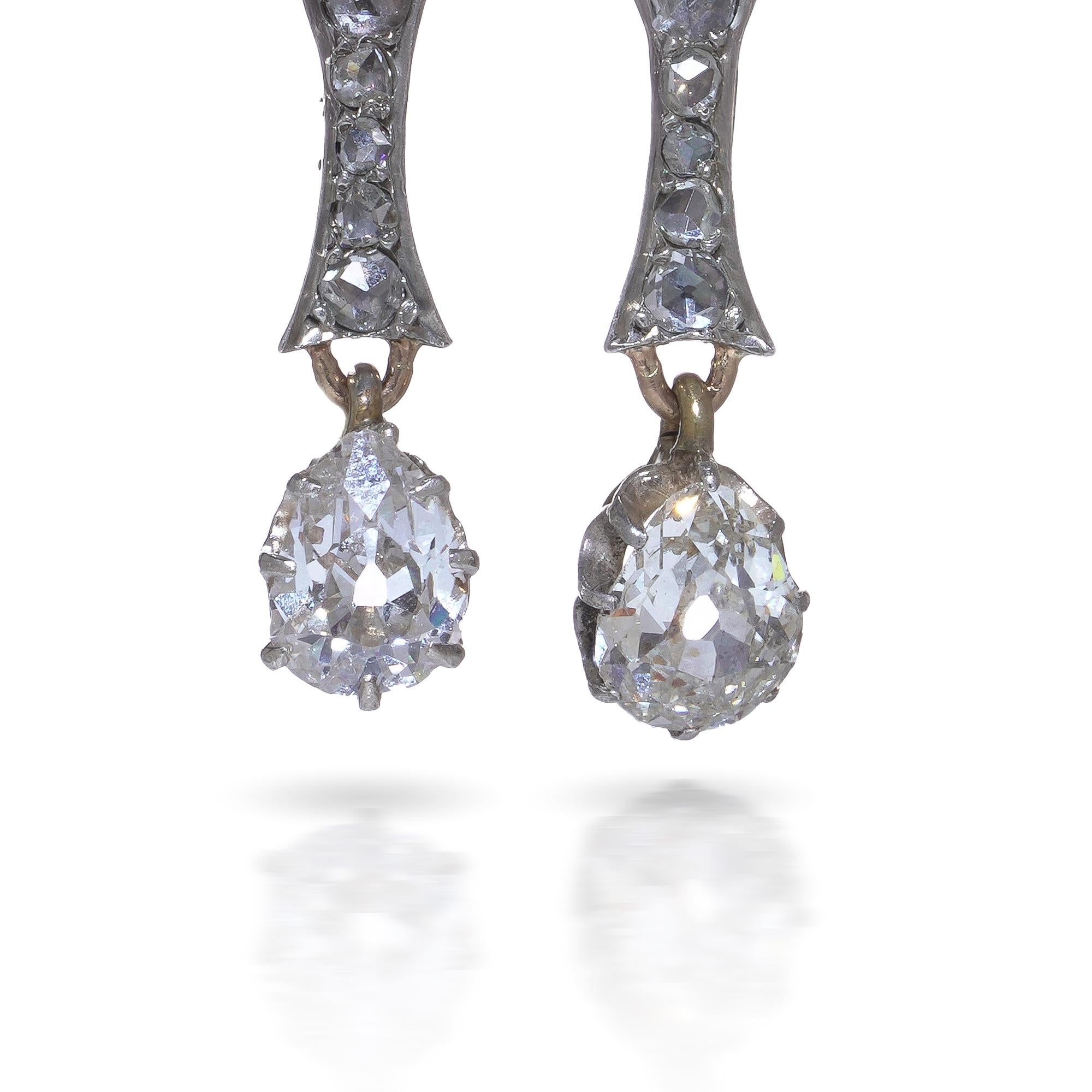 Un paio di orecchini a goccia in oro vittoriano 15 ct che combinano diamanti taglio rosa con un diamante vecchio taglio europeo a forma di pera alla base. Il design segue l'estetica classica del tardo XIX secolo, con spalle dolcemente curve