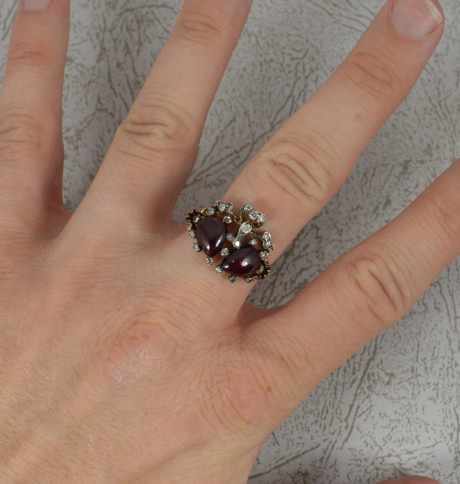 A stunning quality double heart design cluster ring.
A fantastic quality piece of mid to late Victorian era.
Designed with two pear shaped garnet cabochon stones with natural round eight cut diamonds surrounding.
Fine yellow gold patterned