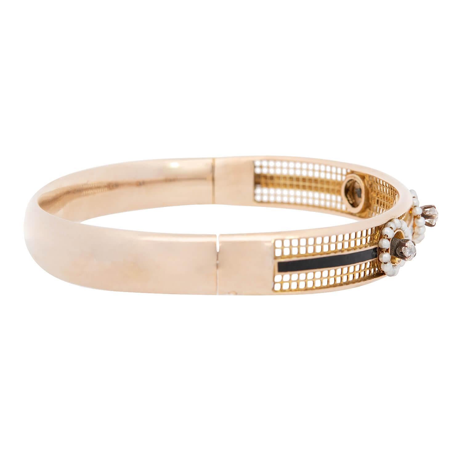A stunning bangle bracelet from the Victorian era (ca1880)! Crafted in 15k yellow gold, the front surface of the bangle features 3 flower motifs. The flowers are centered by old mine cut diamonds, which rest within four-prong settings. The petals of