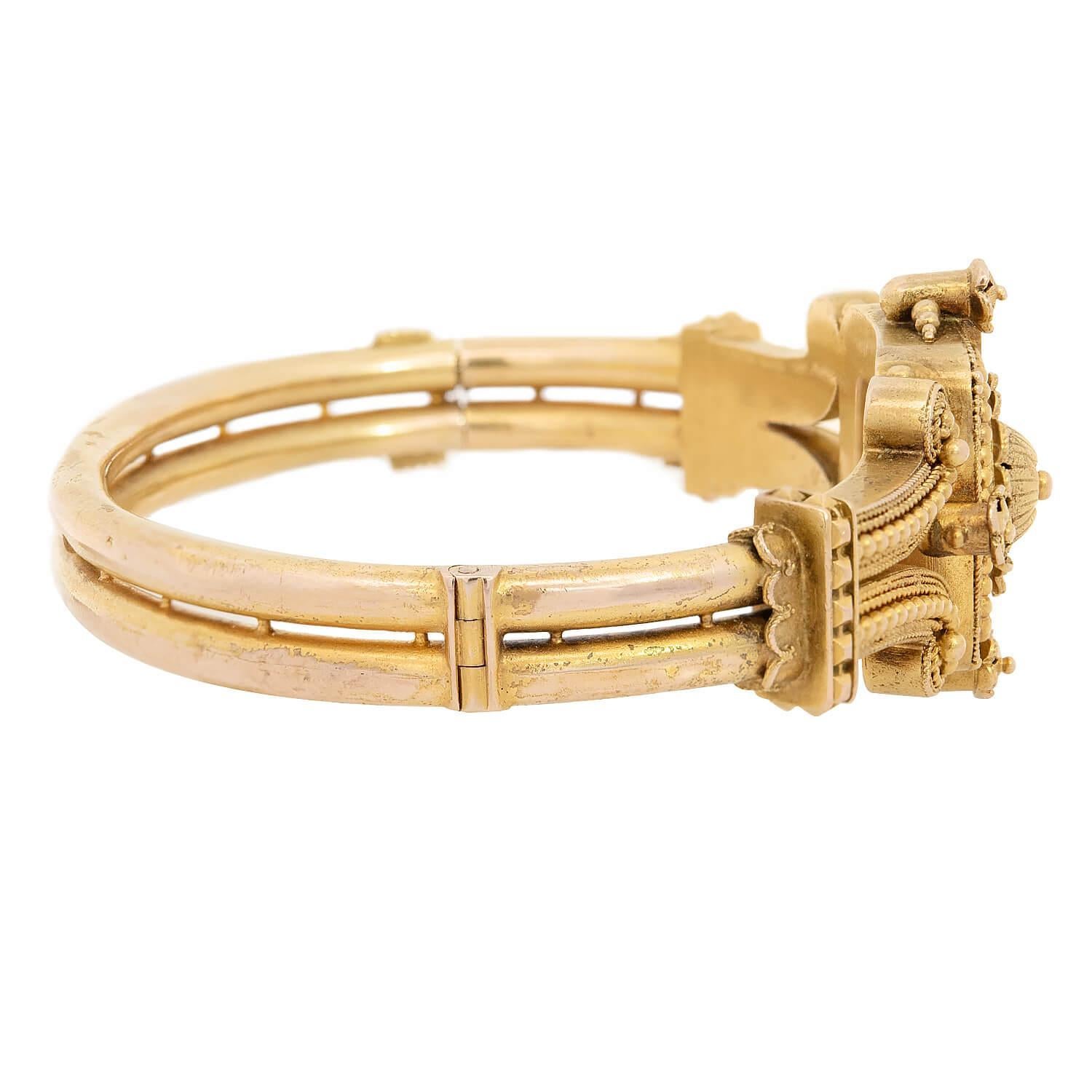 A gorgeous gold bangle bracelet from the Victorian (ca1880) era! Crafted in vibrant 15k yellow gold, this bangle is decorated with intricate Etruscan wirework and raised details. The square-shaped centerpiece of the bracelet is square-shaped,