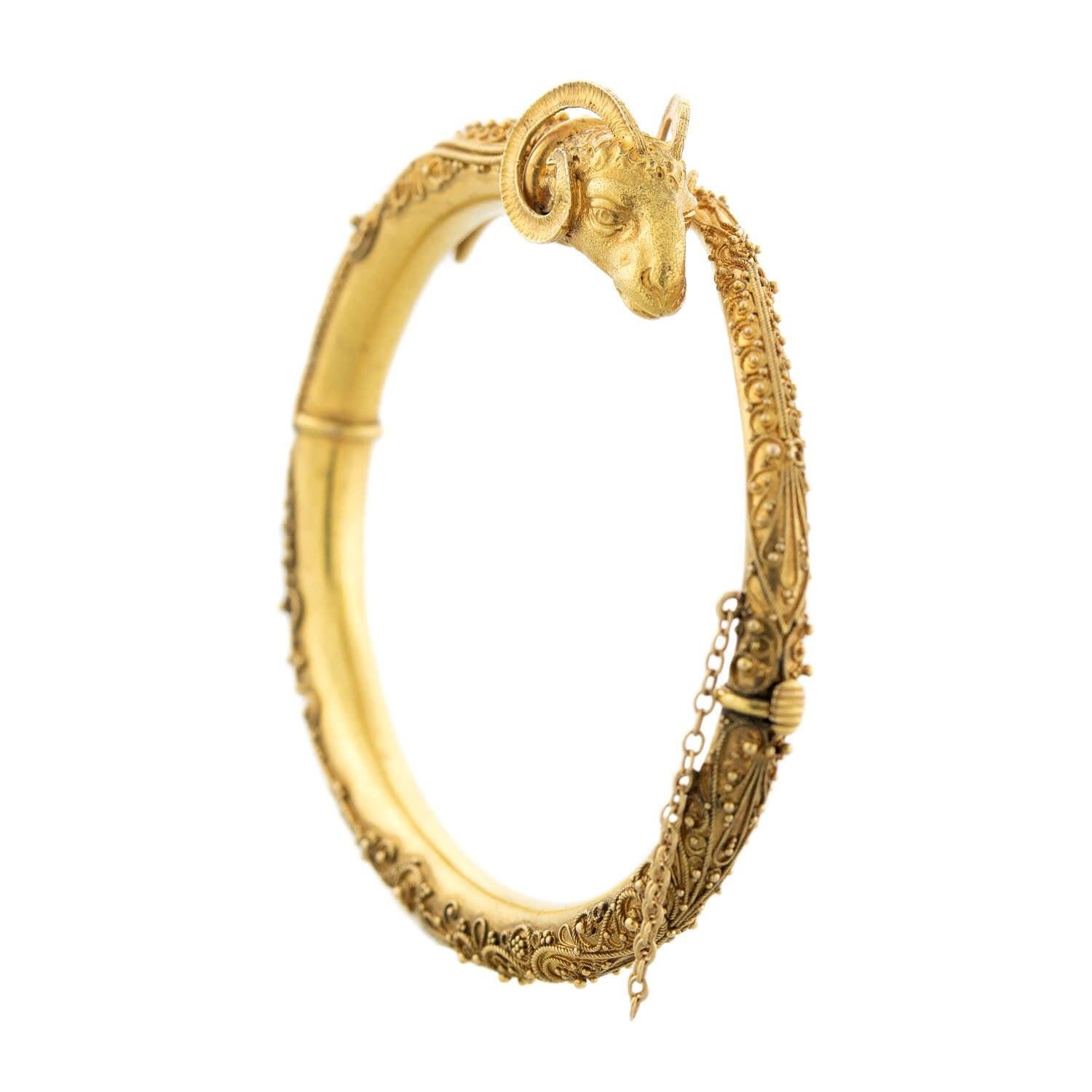 An impressive statement bracelet from the Victorian (ca1880) era! Crafted in 15k gold, the bangle incorporates a ram's head motif into a stylish bypass design with his own tail. The 3-dimensional ram's head is incredibly detailed, including curling