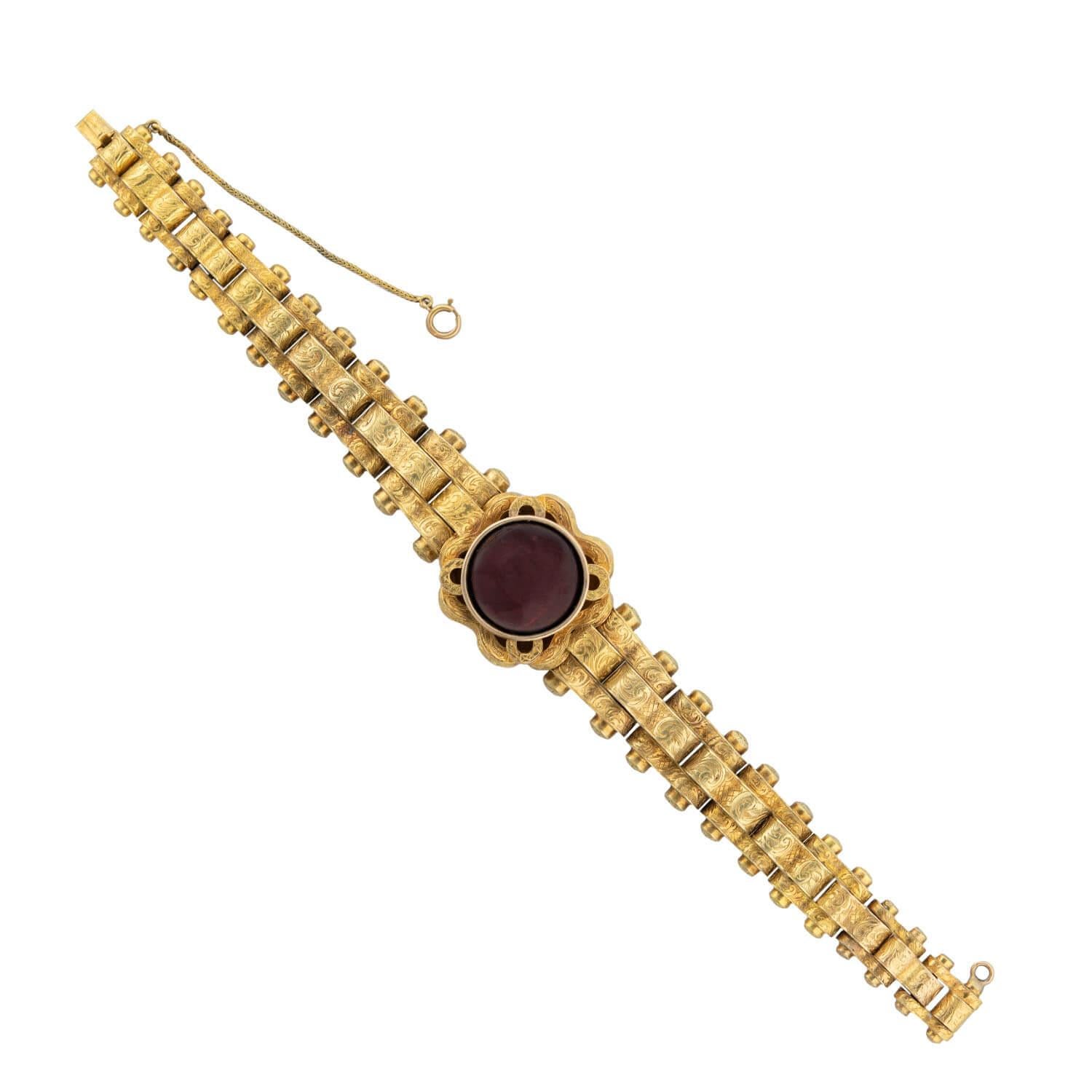 A stunning and artistic bracelet from the Victorian (ca1880) era! This jaw-dropping piece is crafted in 15k yellow gold and is comprised of a series of articulated bike chain-style links. The centerpiece of the bracelet features a large deep red