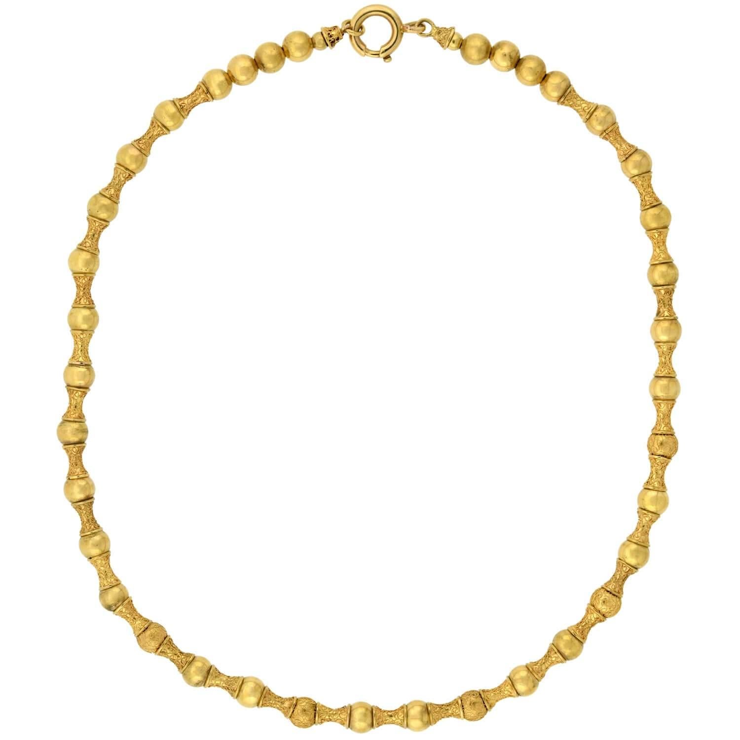 A fantastic Etruscan beaded necklace from the Victorian (ca1880s) era! This beautiful and unique piece is crafted in vibrant 15kt yellow gold and comprised of a pattern of alternating beads. The beads, all strung on a braided gold chain, display a