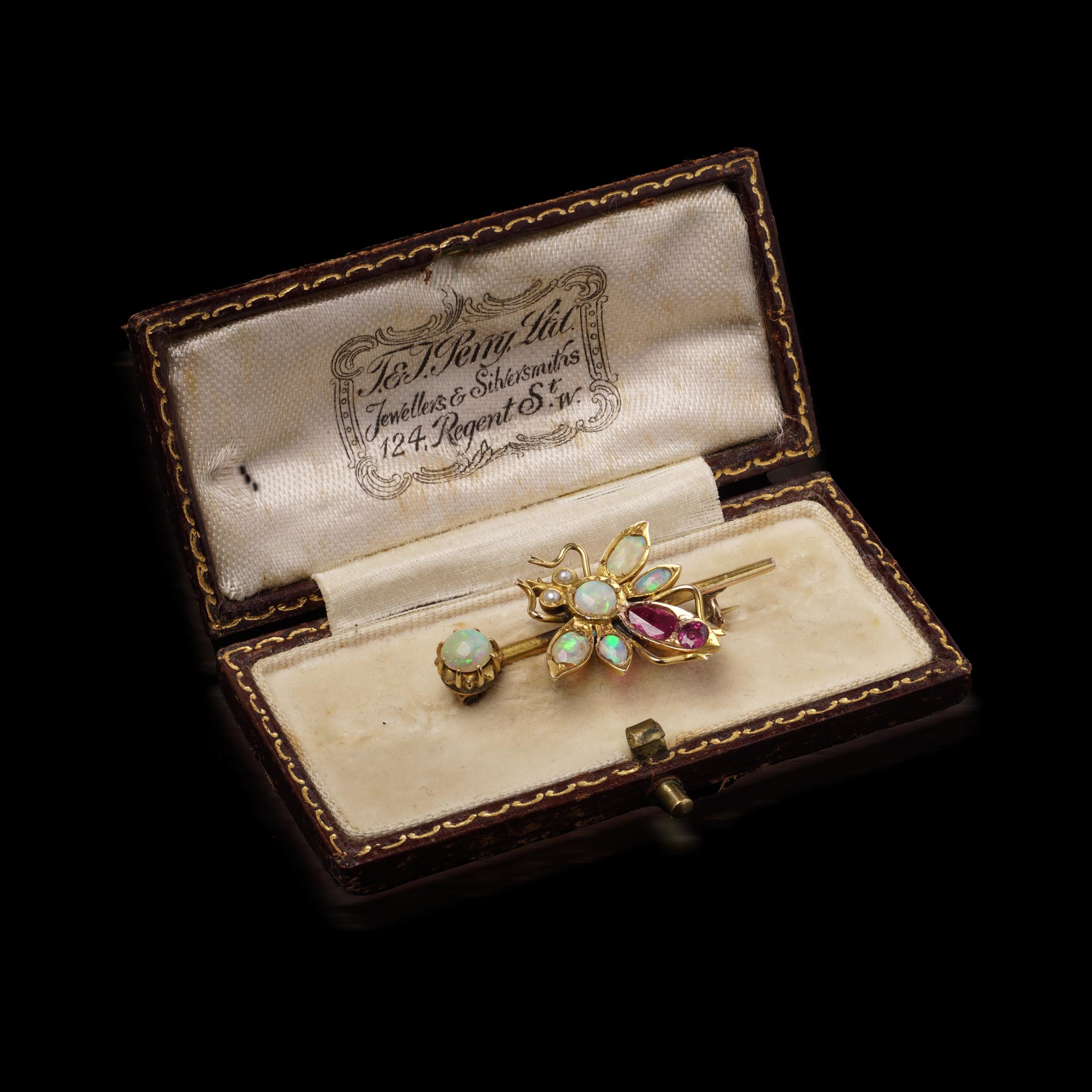 Antique Victorian 15kt Gold Opal and Ruby Brooch
Circa 1880's

Specifications:
Era: Victorian
Material: 15kt Yellow Gold
Gemstones:
Opals (various sizes, vibrant play-of-color)
Rubies (deep red, faceted)
Small seed pearls
Dimensions: 3.8 x 2 x 0.8