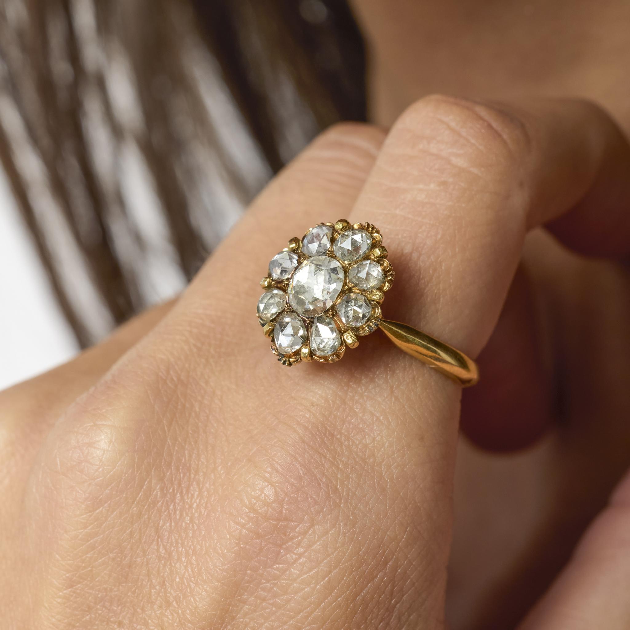 Dieser geschichtsträchtige viktorianische Ring zeigt neun leuchtende Diamanten im Rosenschliff, die in einem zeitlosen floralen Motiv angeordnet sind. Die sanft gewölbten Facetten jedes Diamanten fangen das Licht mit einem romantischen Schimmer ein,