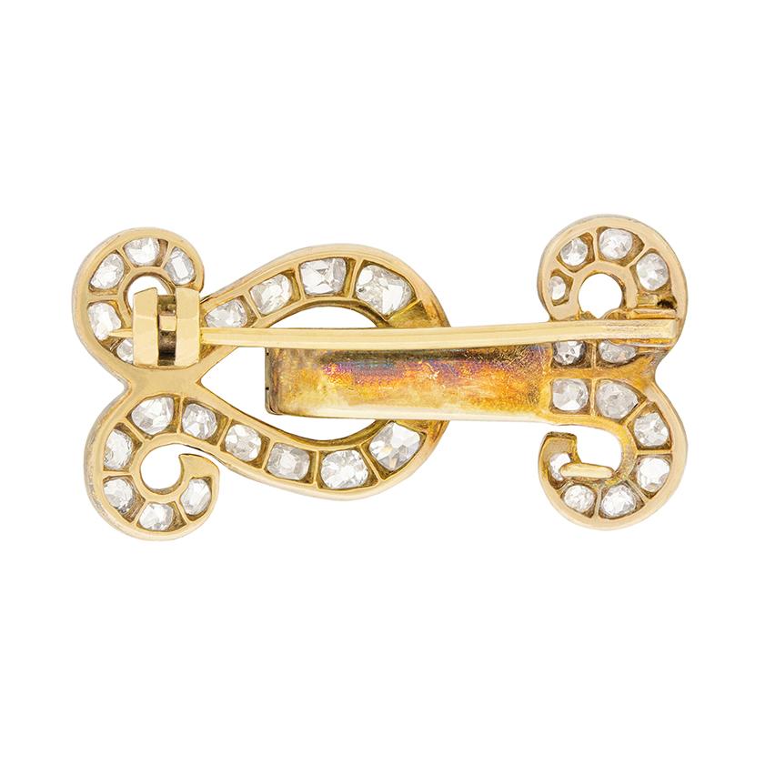 This glittering diamond brooch takes the form of interlocking scrolls. Forty six old cut diamonds are set in silver, and are H to I in colour and VS to SI in clarity. The back of the brooch is made of 15 carat rose gold, a combination of precious