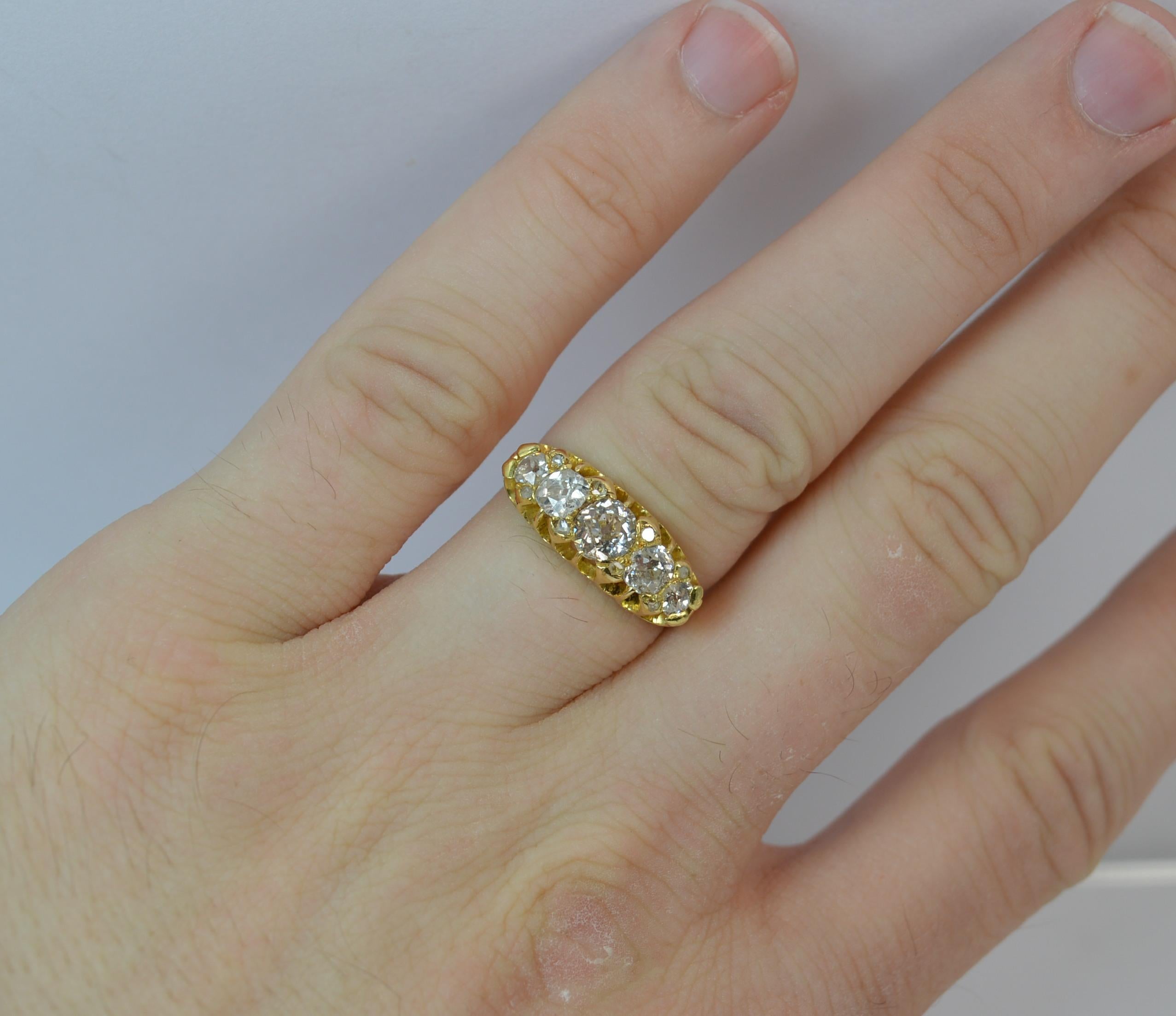 

A British hallmarked Victorian 18ct gold and diamond ring.

A five old cut diamond design of graduated size with diamond chip spacers in between.

Total carat weight approx 1.25 carats. 5mm - 5.3mm central diamond.

18mm x 7mm cluster head. Bright