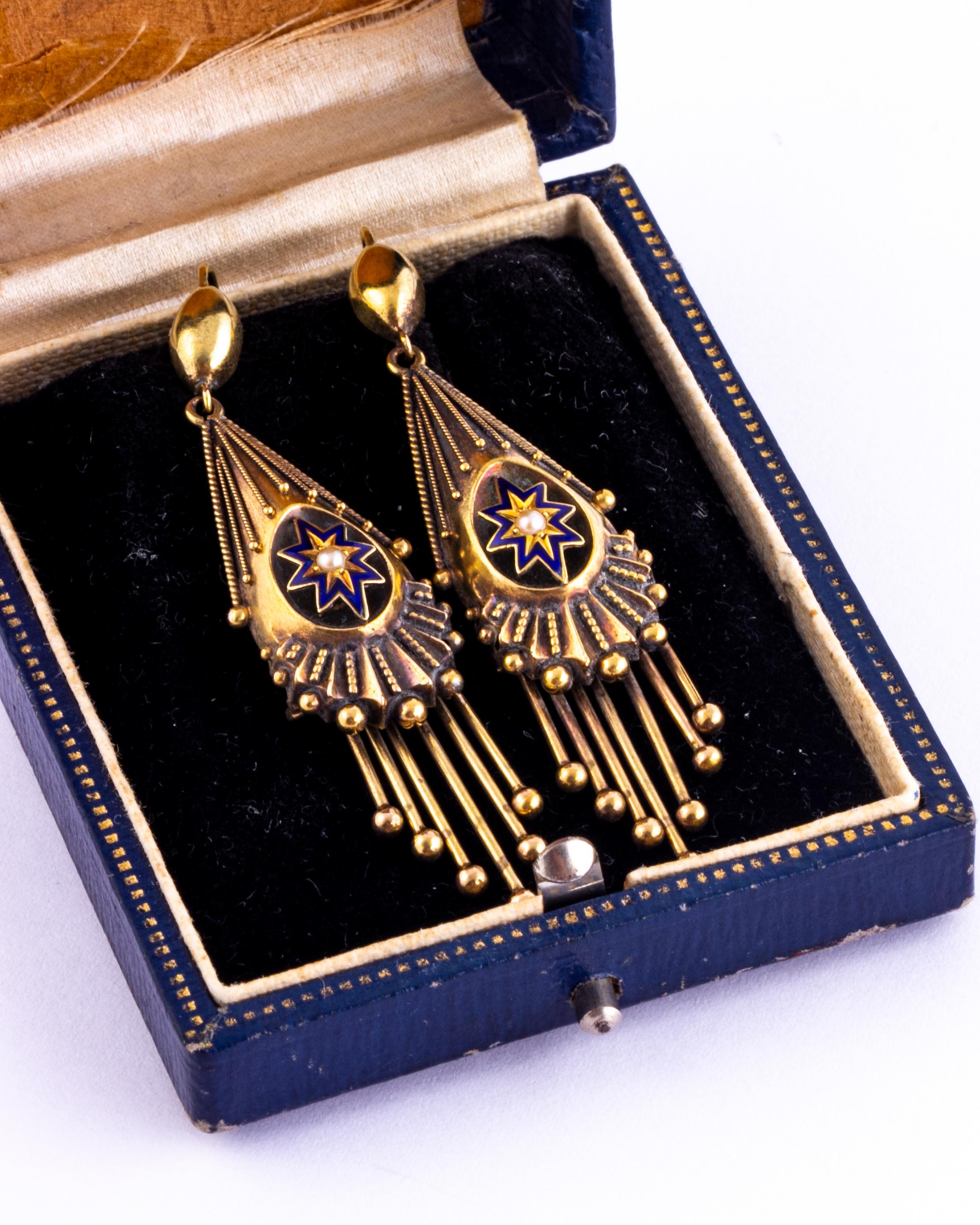These stunning earrings have a starburst design at the centre which is decorated with blue enamel and a seed pearl. The main earrings themselves have intricate rope twist detail and orbs hanging from them. Modelled in 18ct gold. 

Drop From Ear: