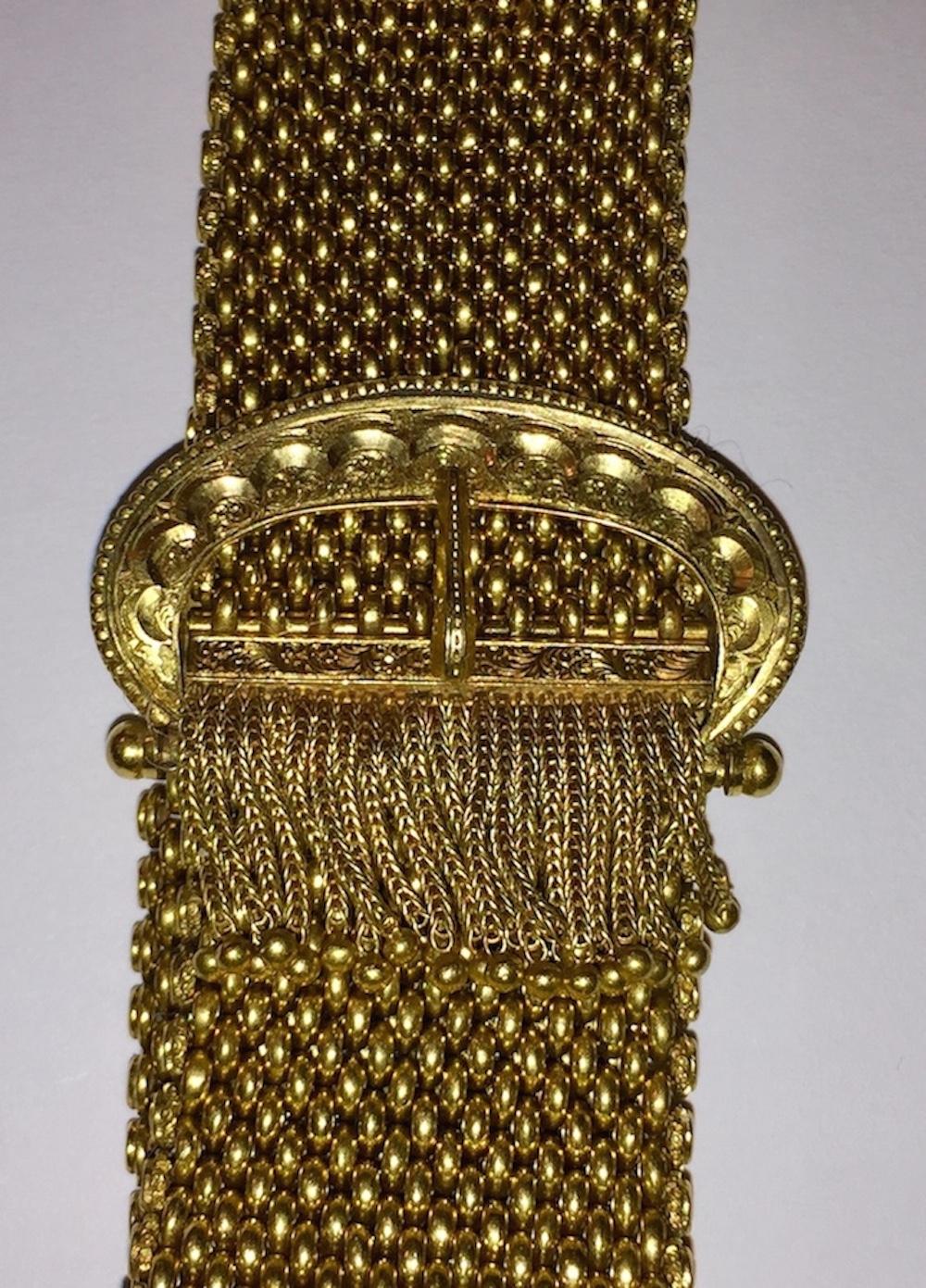 Unmarked 18 karat gold mesh buckle bracelet with fringe end. Adjustable, closes by pressing in both button on the two sides, measures 10” long and 1.75” wide. Weighs, 68.7 grams
